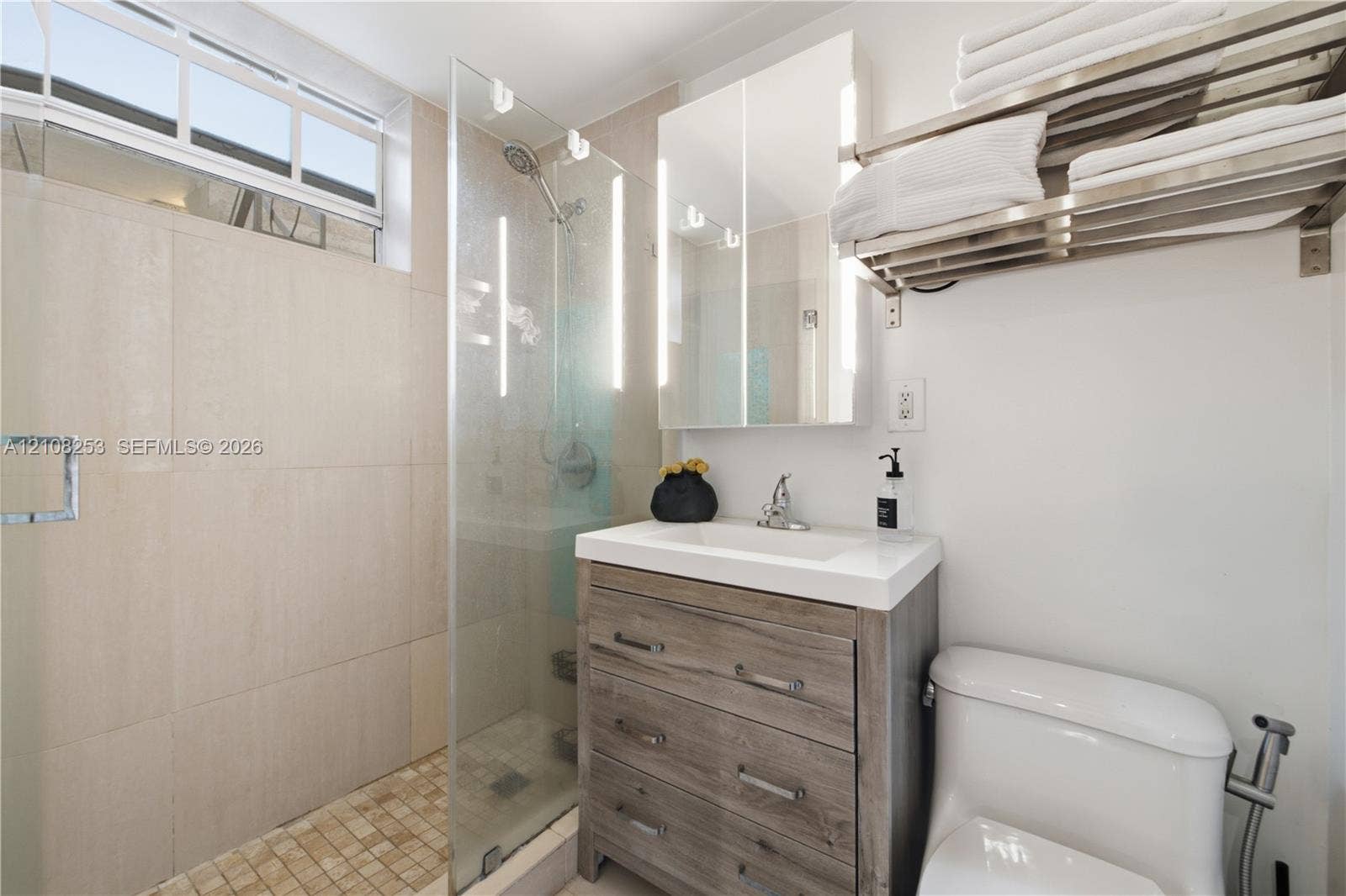 1330 Drexel Avenue, #102, Miami Beach, FL 33139 Walk-in shower featuring floor-to-ceiling tile, frameless glass enclosure, and a handheld shower head
