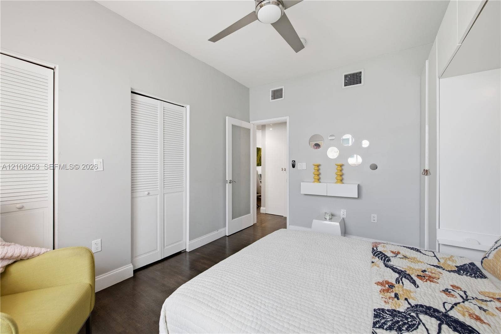 1330 Drexel Avenue, #102, Miami Beach, FL 33139 Wood-finish flooring, white louvered closet doors, modern ceiling fan with integrated lighting, and a white interior door with a frosted glass pane
