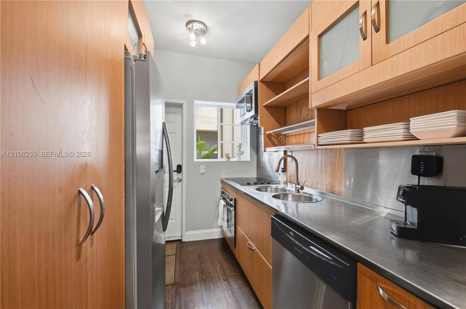 1330 Drexel Avenue, #102, Miami Beach, FL 33139 Galley kitchen featuring wood-finish cabinetry, stainless steel countertops, integrated stainless steel appliances, and wood-finish flooring