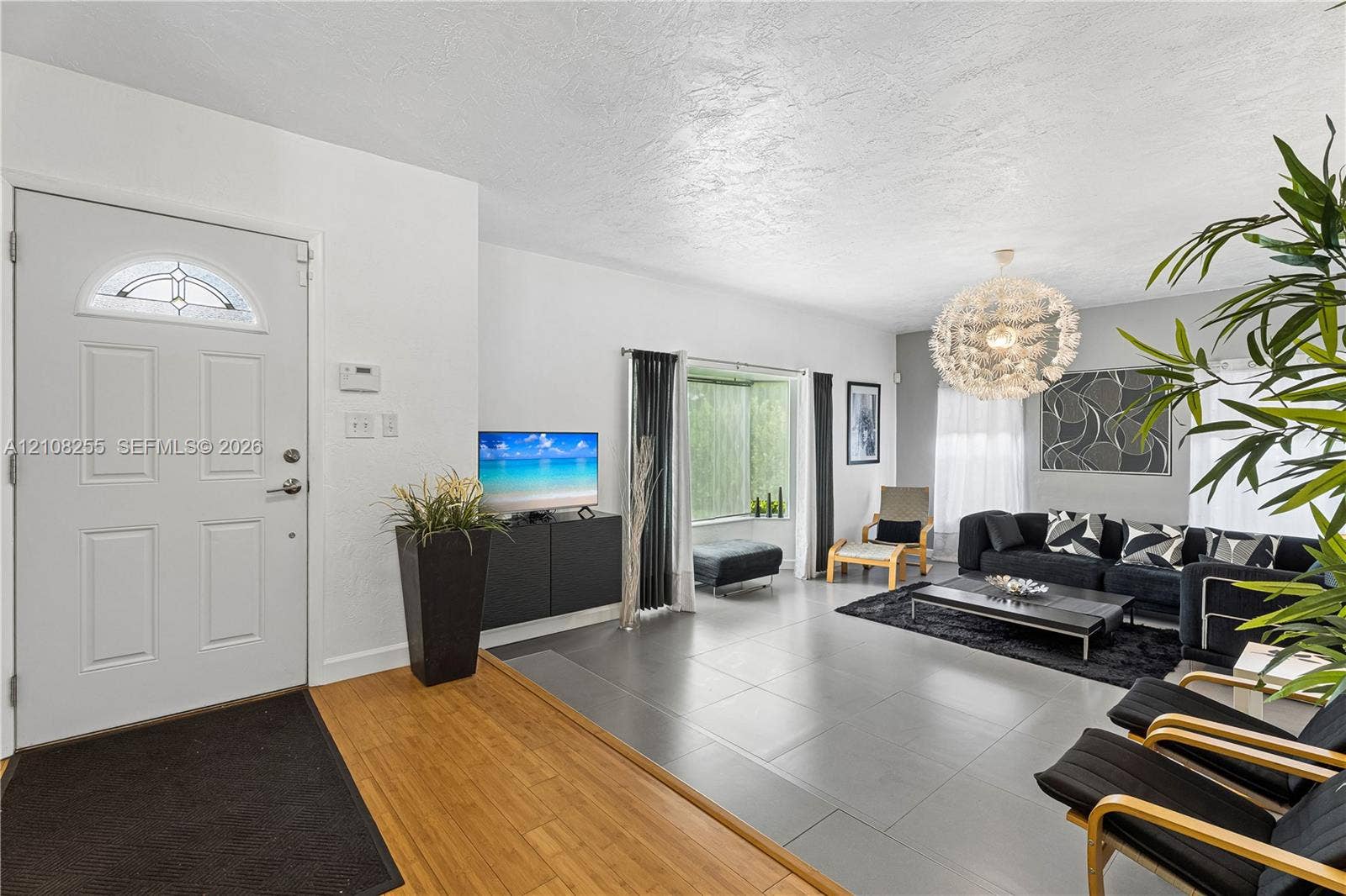 1650 NE 171st Street, North Miami Beach, North Miami Beach, FL 33162 Entrance featuring a semi-circular transom window, large-format tile flooring, wood-finish entryway flooring, and a spherical tiered chandelier