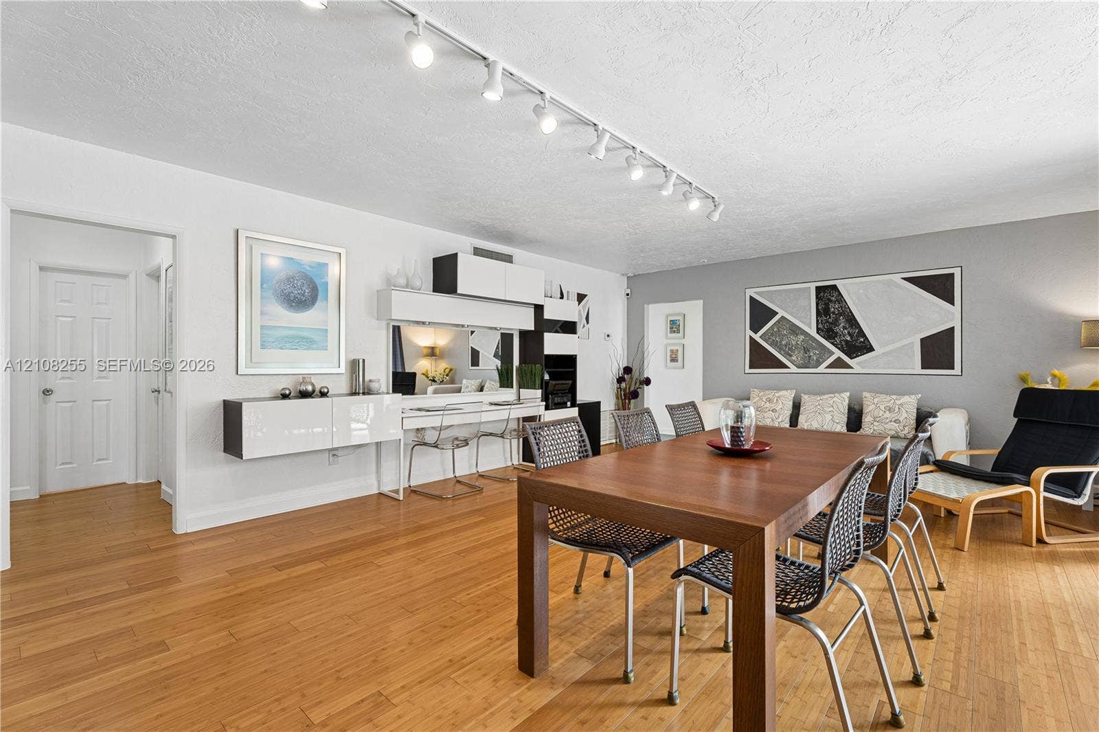 1650 NE 171st Street, North Miami Beach, North Miami Beach, FL 33162 Living area featuring wood-finish flooring, ceiling-mounted track lighting, and built-in wall cabinetry with integrated desk surface