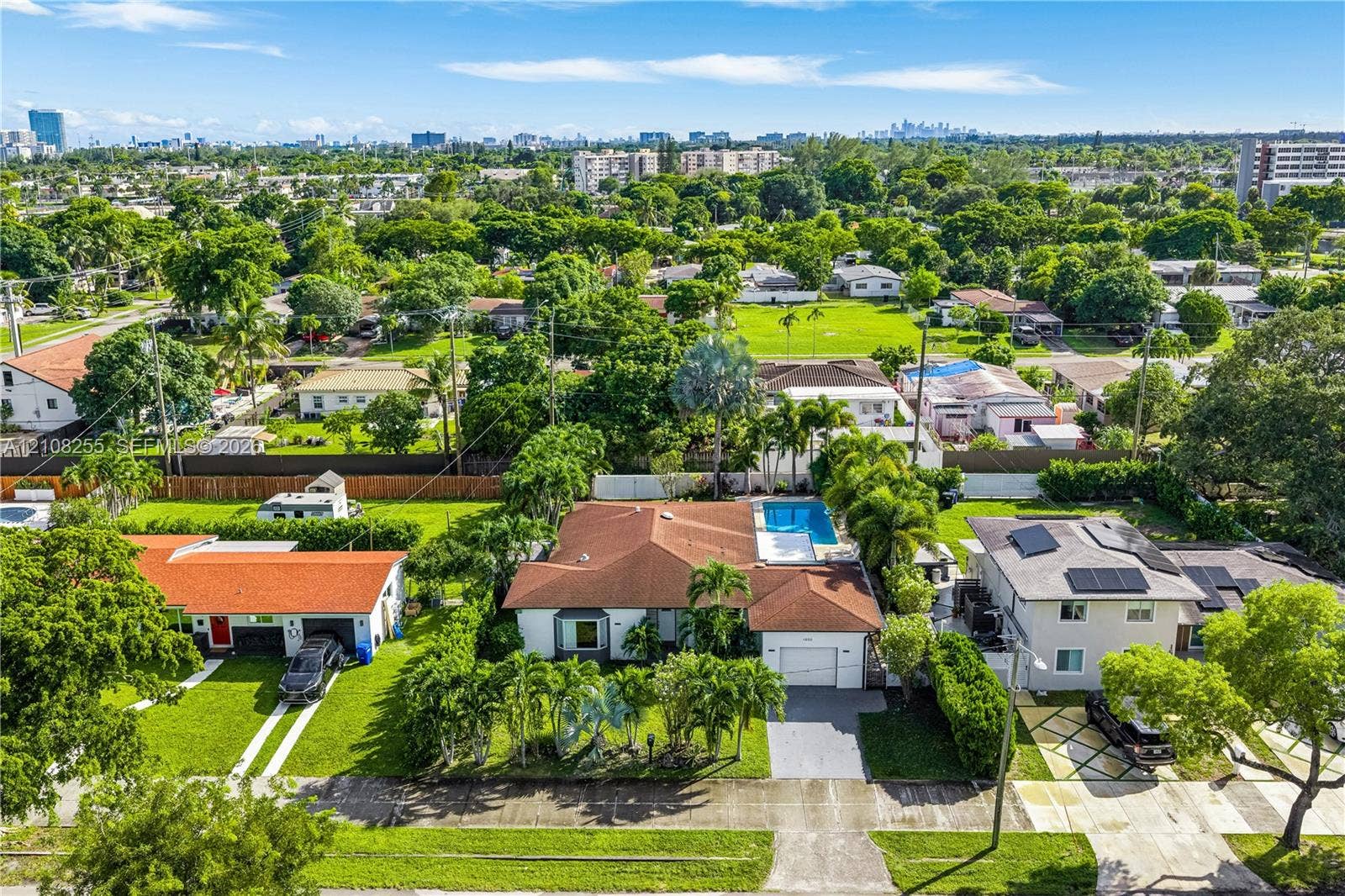 1650 NE 171st Street, North Miami Beach, North Miami Beach, FL 33162 Single-story residence featuring a tile roof, built-in swimming pool, paved driveway, and mature landscaping