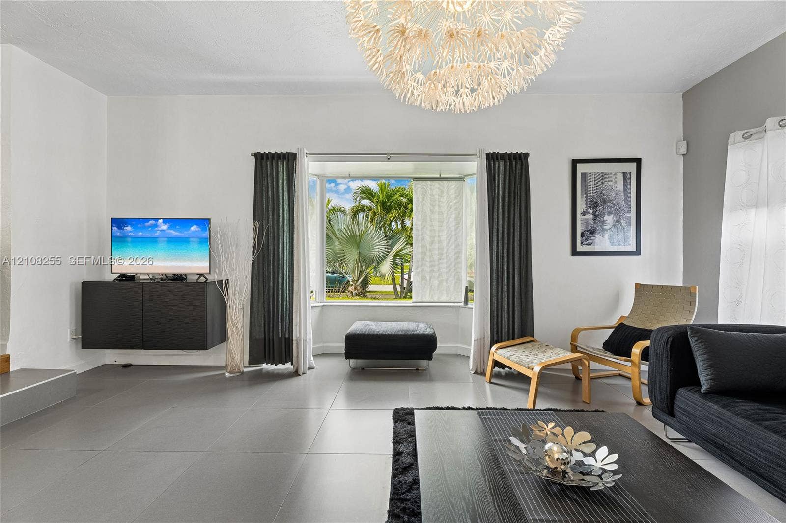 1650 NE 171st Street, North Miami Beach, North Miami Beach, FL 33162 Living space featuring large format tile flooring, a prominent bay window, and a modern tiered chandelier fixture