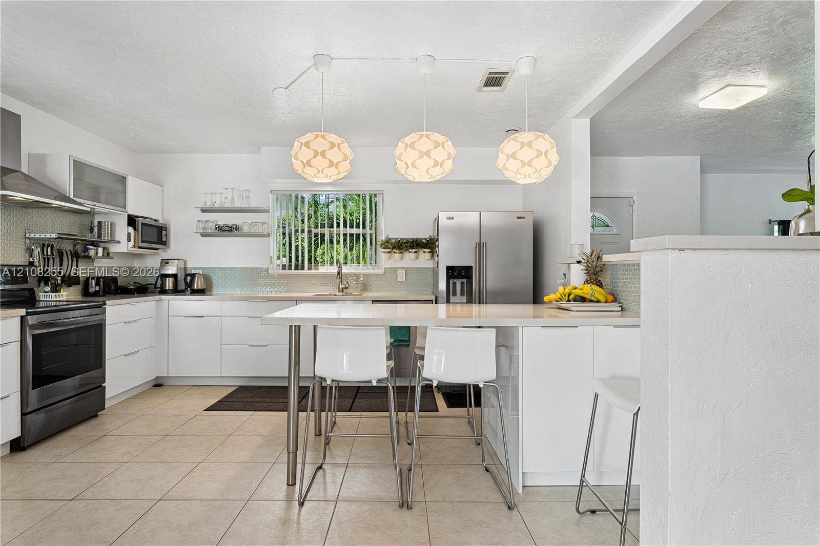 1650 NE 171st Street, North Miami Beach, North Miami Beach, FL 33162 Kitchen featuring flat-panel white cabinetry, stainless steel appliances, quartz countertops, a tile backsplash, and three suspended geometric pendant lights