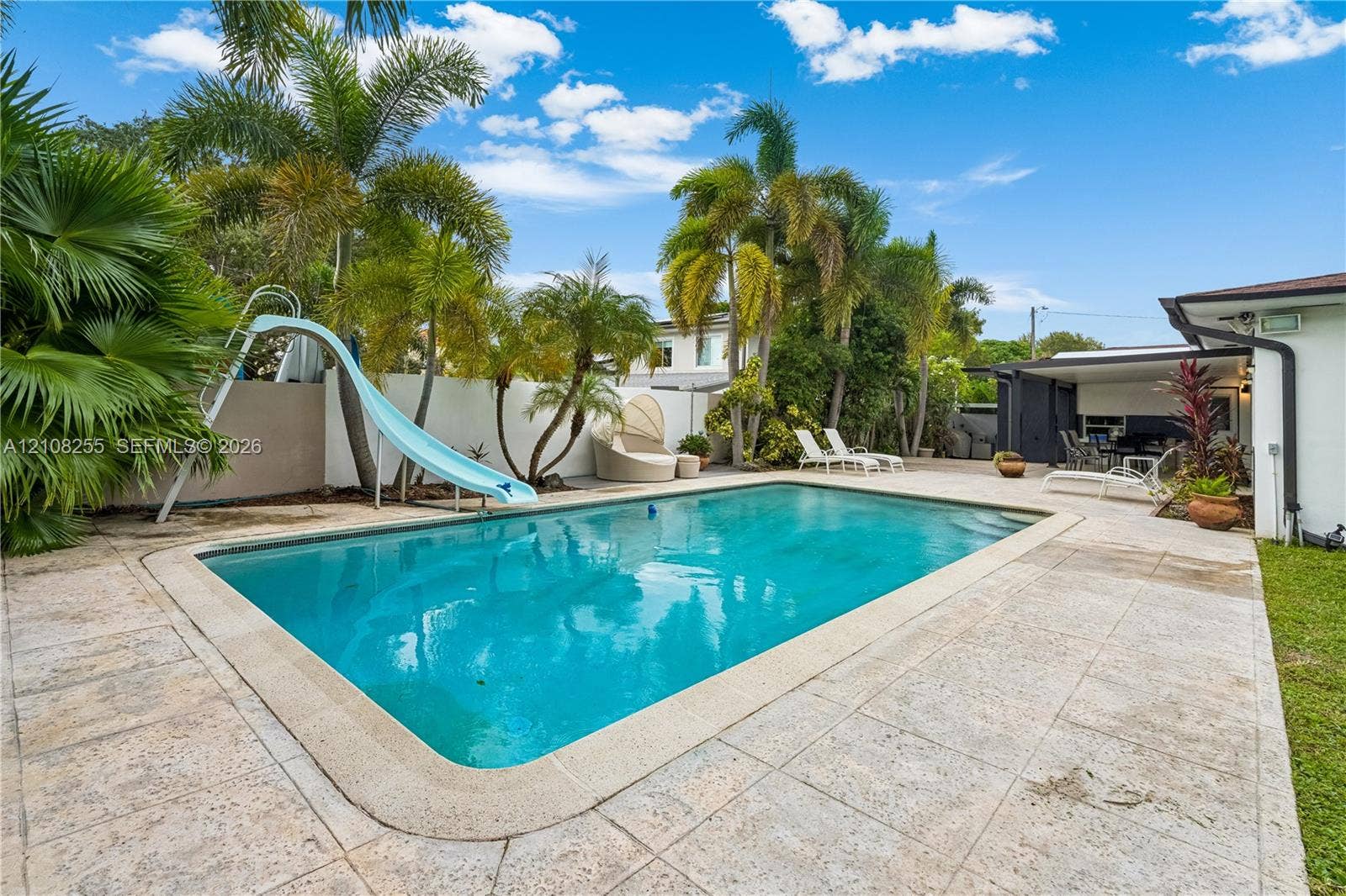 1650 NE 171st Street, North Miami Beach, North Miami Beach, FL 33162 Inground swimming pool with slide, stone-tiled patio, and mature palm trees