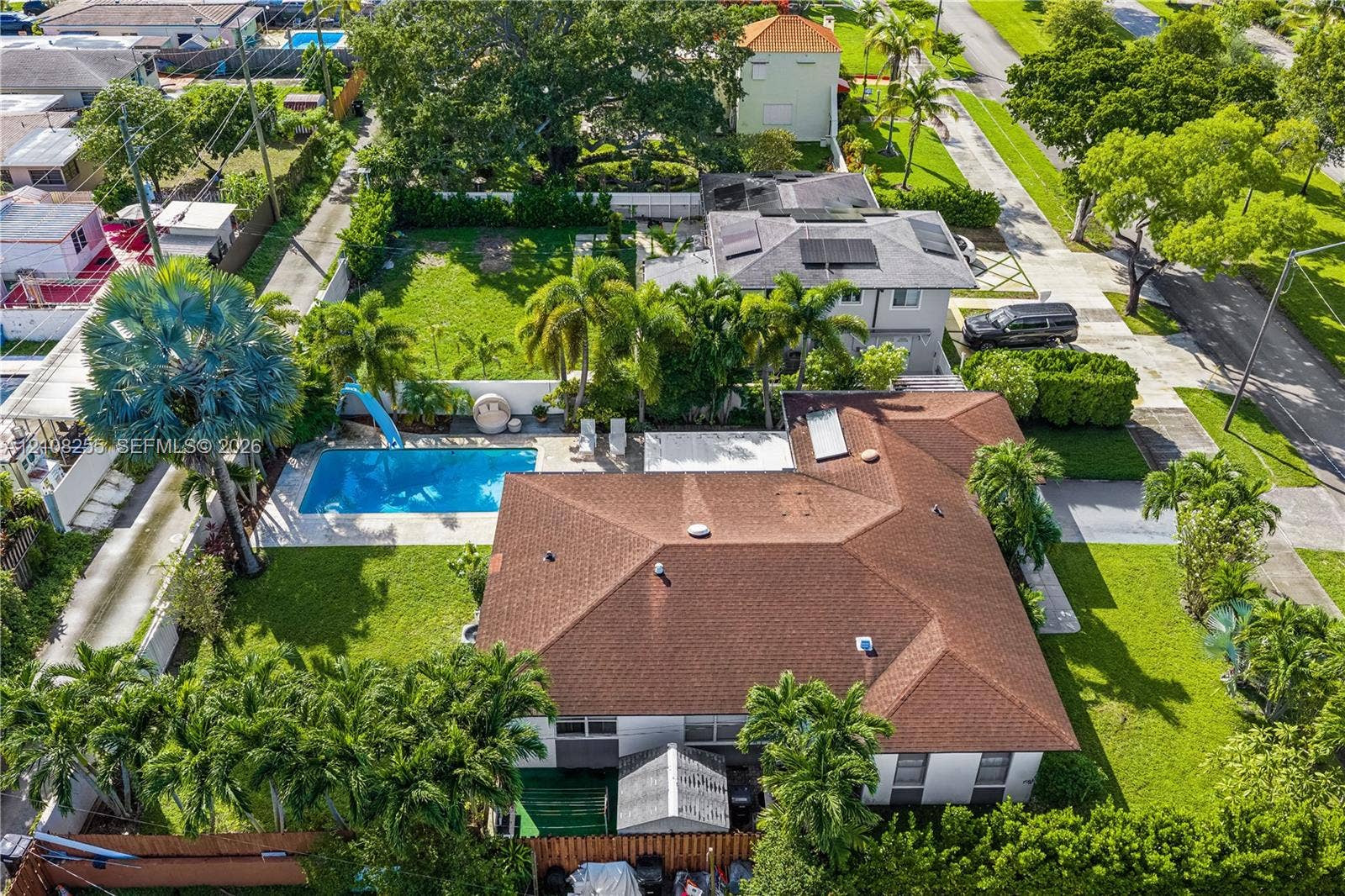 1650 NE 171st Street, North Miami Beach, North Miami Beach, FL 33162 Aerial perspective featuring a shingled roofline, in-ground swimming pool, manicured lawn, and mature perimeter landscaping
