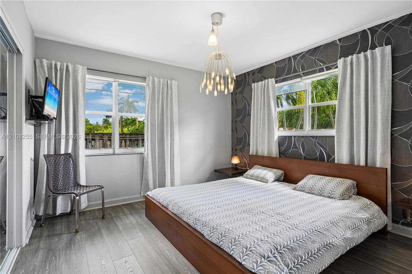 1650 NE 171st Street, North Miami Beach, North Miami Beach, FL 33162 Wood-finish flooring, accent wall with patterned wall covering, multi-light pendant fixture, and large windows