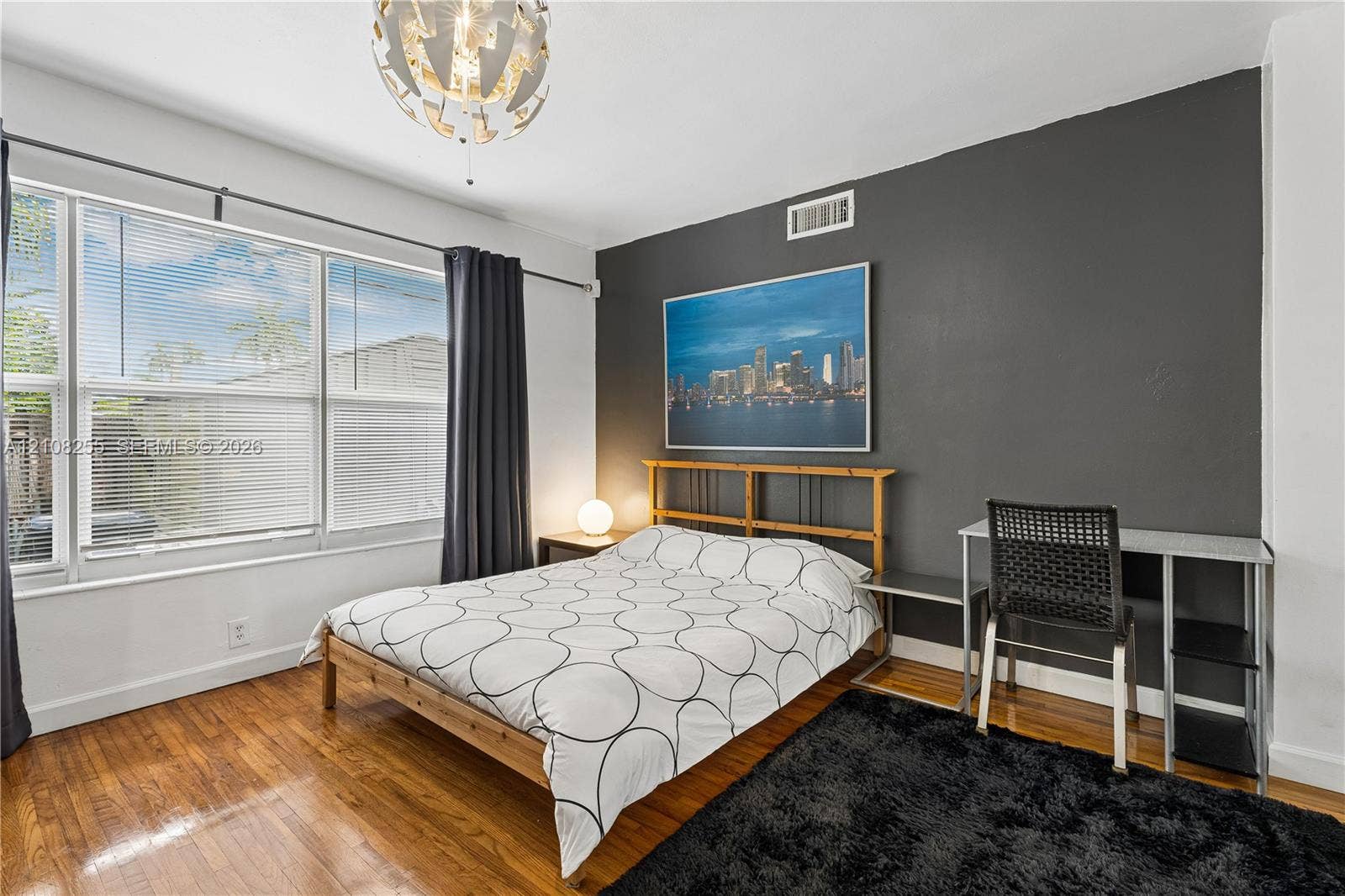 1650 NE 171st Street, North Miami Beach, North Miami Beach, FL 33162 Room featuring wood-finish flooring, a charcoal accent wall, a large window with blinds, and a contemporary spherical chandelier