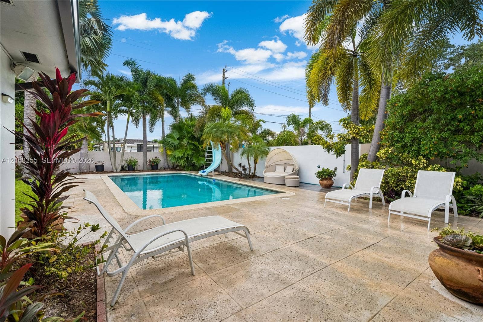 1650 NE 171st Street, North Miami Beach, North Miami Beach, FL 33162 Outdoor space featuring a swimming pool, concrete patio, perimeter wall, and mature palm trees