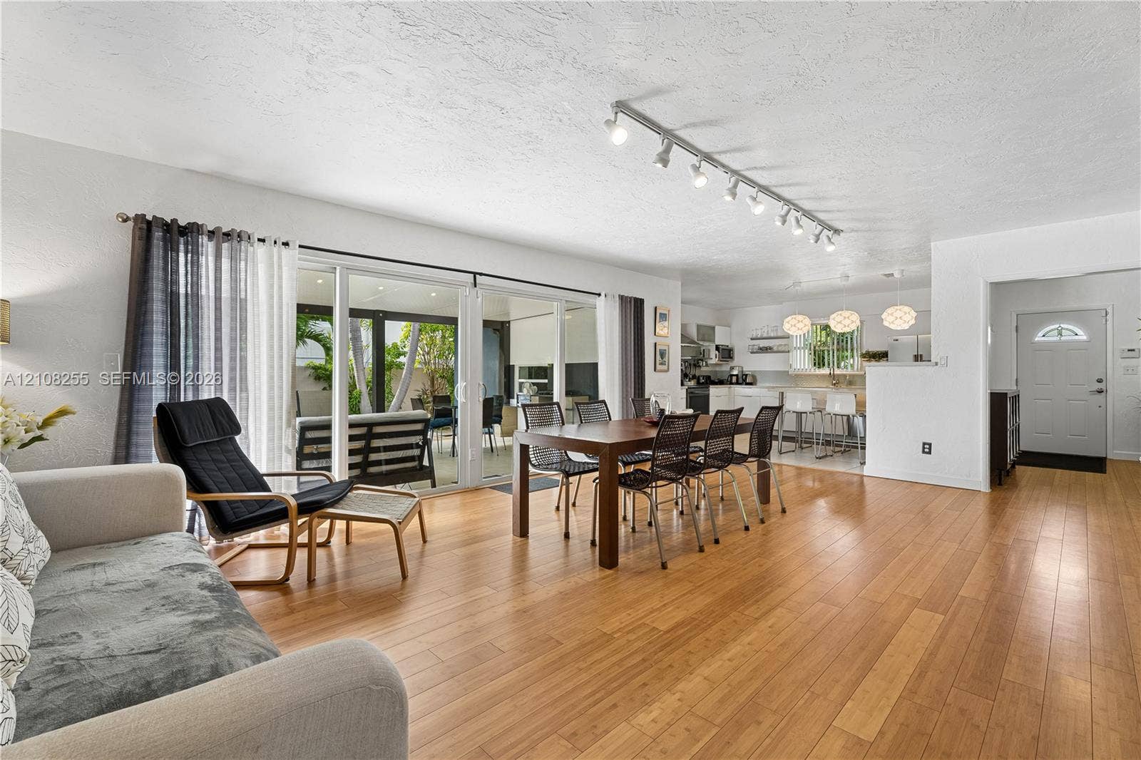 1650 NE 171st Street, North Miami Beach, North Miami Beach, FL 33162 Open-concept interior with wood-finish flooring, sliding glass doors, adjustable track lighting, and a six-panel entry door