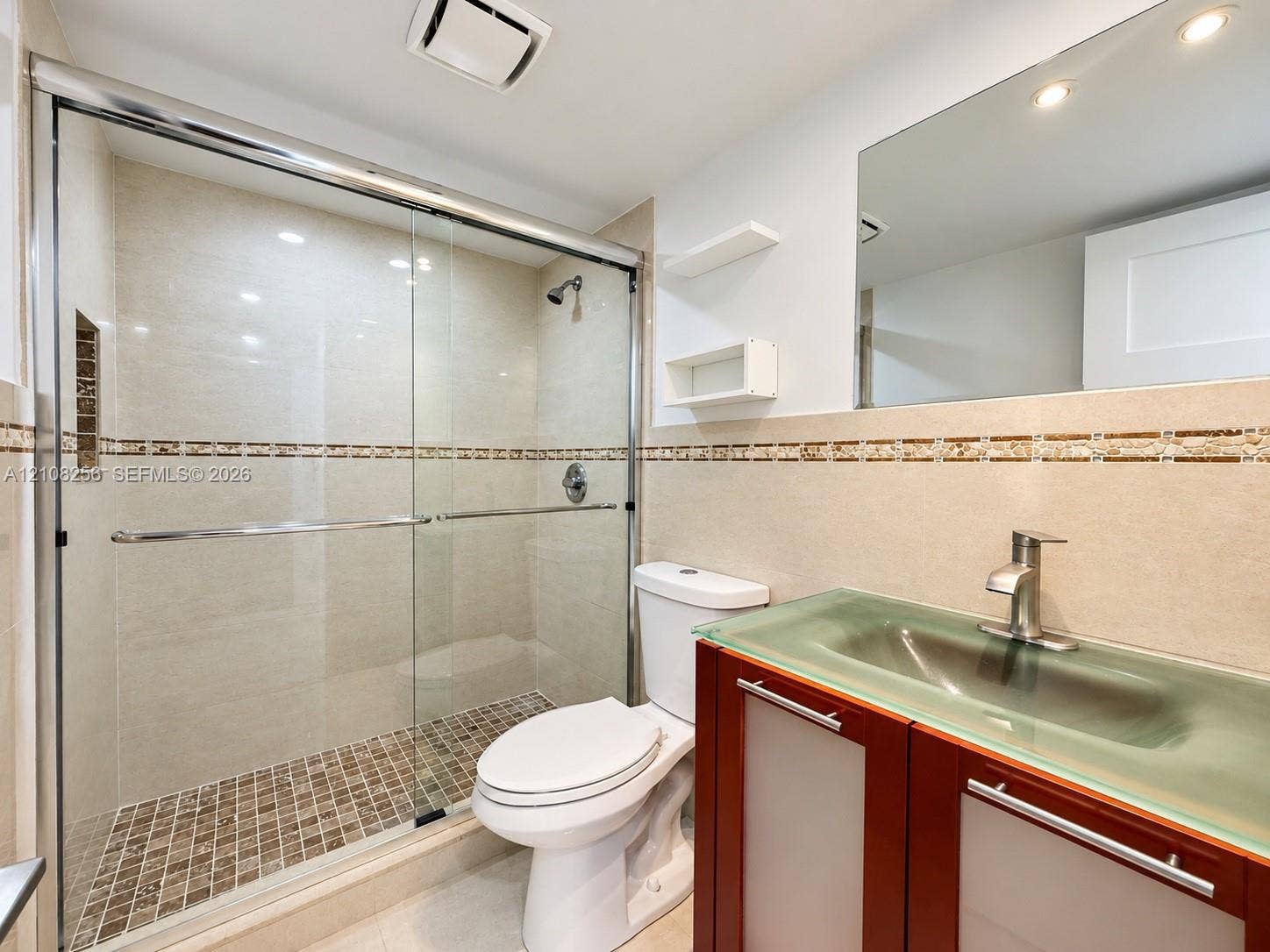 9350 Fontainebleau Boulevard, #110, Miami, Miami, FL 33172 Bathroom featuring a glass-enclosed shower with mosaic tile flooring, a vanity with a frosted glass integrated sink, a large wall-mounted mirror, and decorative tile accents