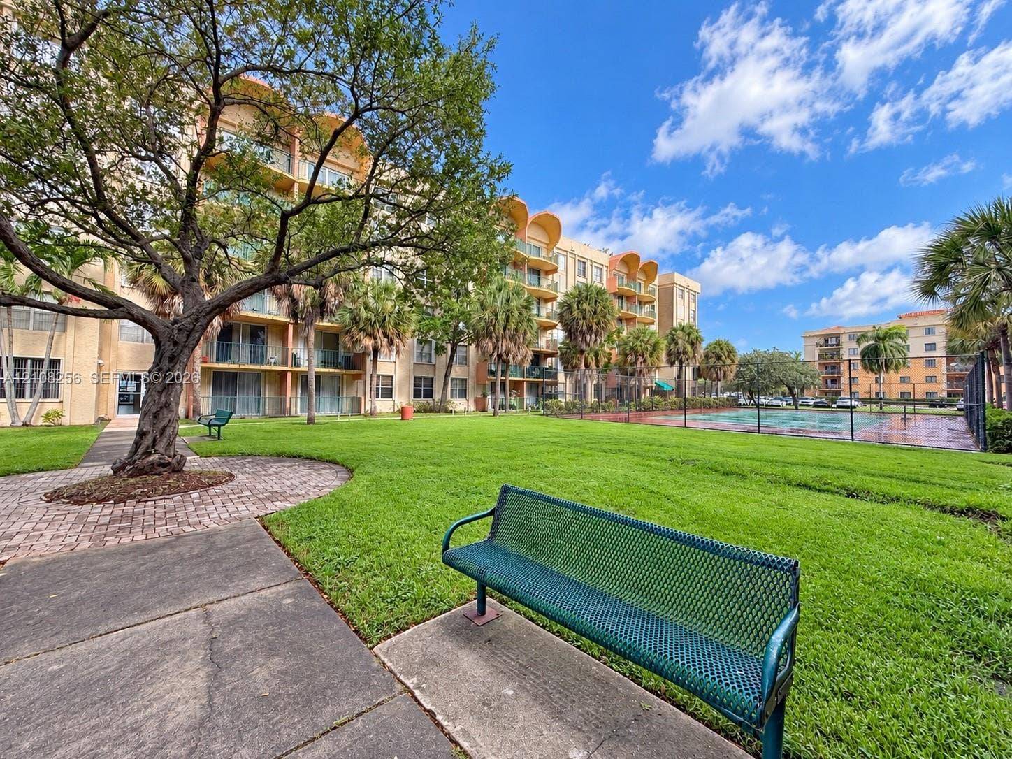 9350 Fontainebleau Boulevard, #110, Miami, Miami, FL 33172 Grounds featuring manicured lawn, mature trees, concrete walking paths, and a fenced recreation court