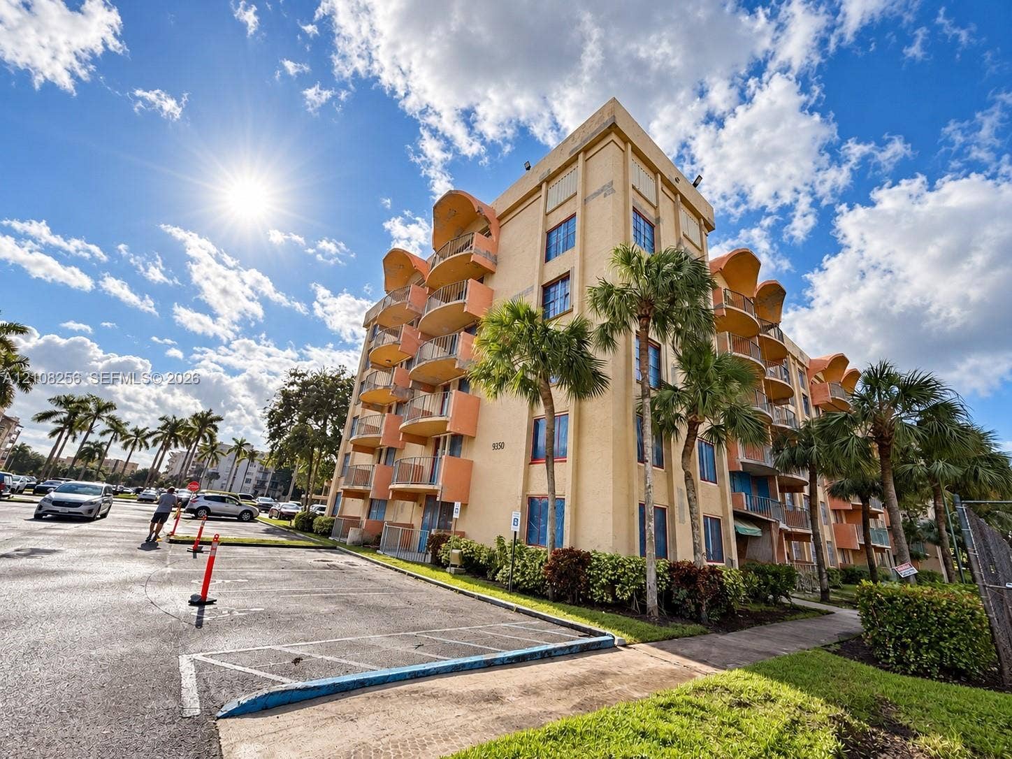 9350 Fontainebleau Boulevard, #110, Miami, Miami, FL 33172 Multi-story building exterior featuring stucco cladding, rounded balconies with railings, and palm tree landscaping