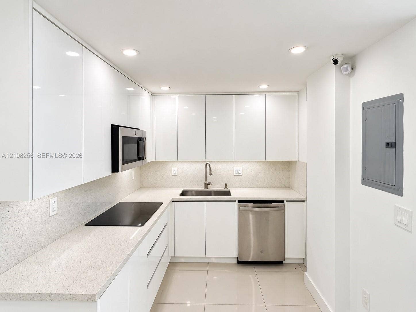 9350 Fontainebleau Boulevard, #110, Miami, Miami, FL 33172 Kitchen featuring high-gloss cabinetry, light-toned stone-finish countertops, stainless steel appliances, a recessed sink with a gooseneck faucet, and porcelain tile flooring
