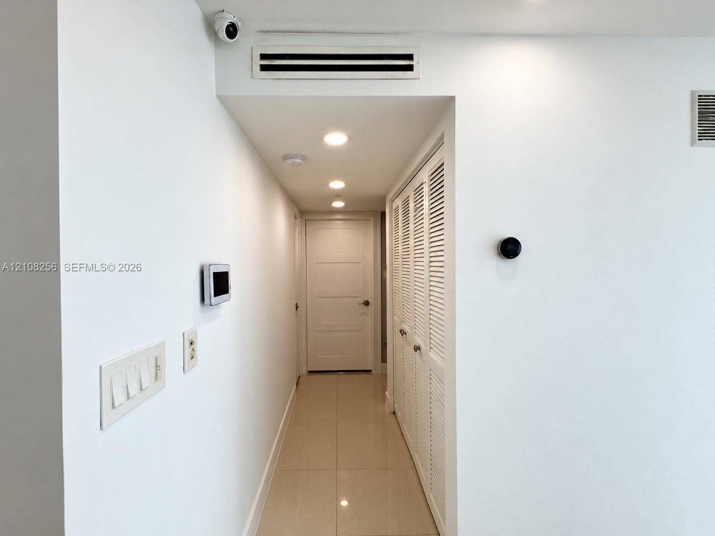 9350 Fontainebleau Boulevard, #110, Miami, Miami, FL 33172 Hallway featuring tile flooring, recessed ceiling lighting, louvered closet doors, and integrated smart home wall-mounted controls