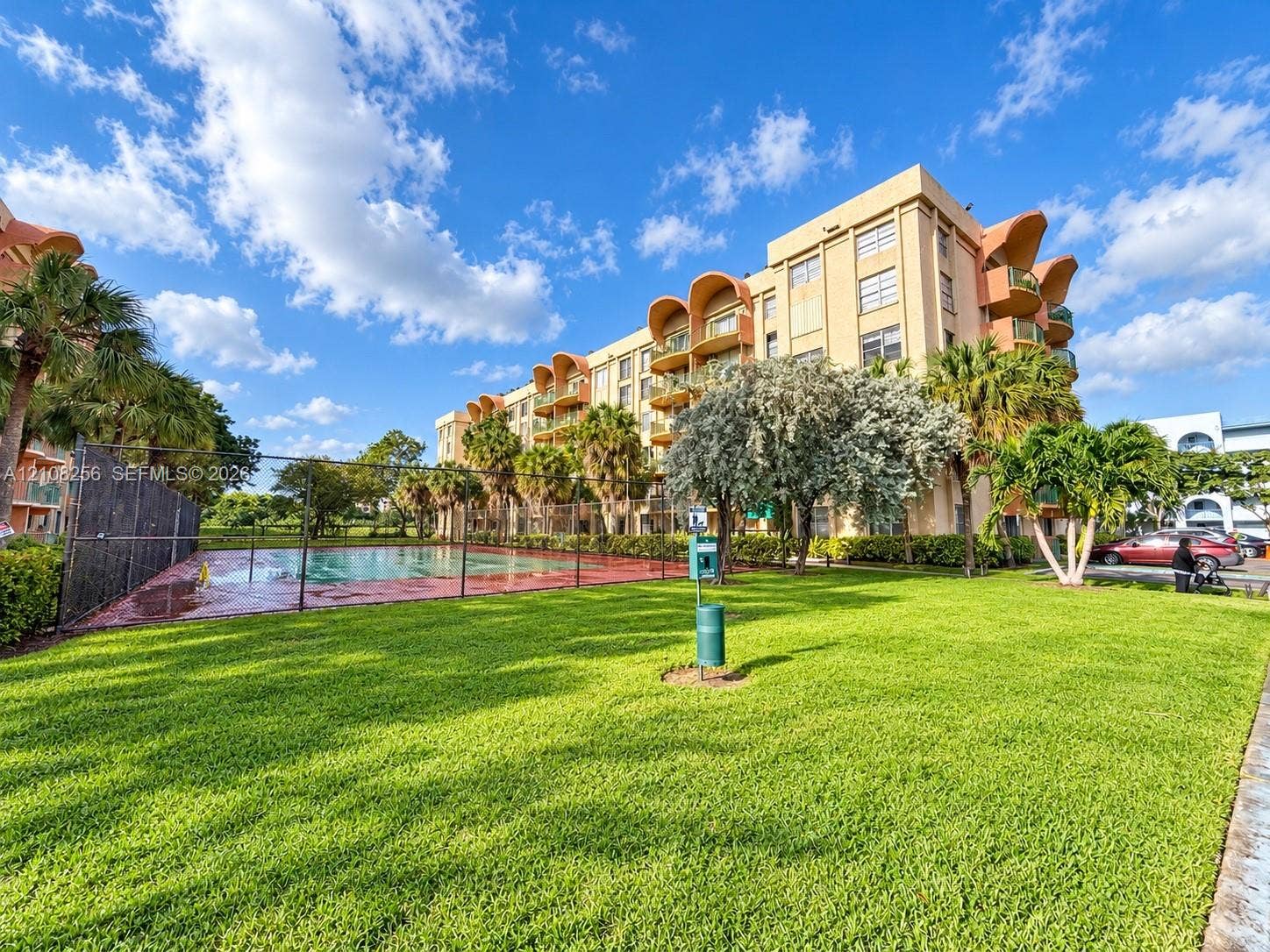 9350 Fontainebleau Boulevard, #110, Miami, Miami, FL 33172 Multi-story building featuring architectural arched balconies, fenced swimming pool, and landscaped green space with mature palm trees