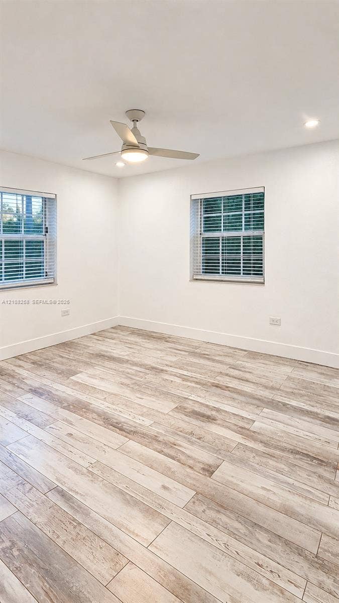 909 NE 111th Street, #909, Biscayne Park, Biscayne Park, FL 33161 Room featuring wood-finish flooring, recessed lighting, and a ceiling fan with integrated light fixture, complemented by two windows with multi-pane glass