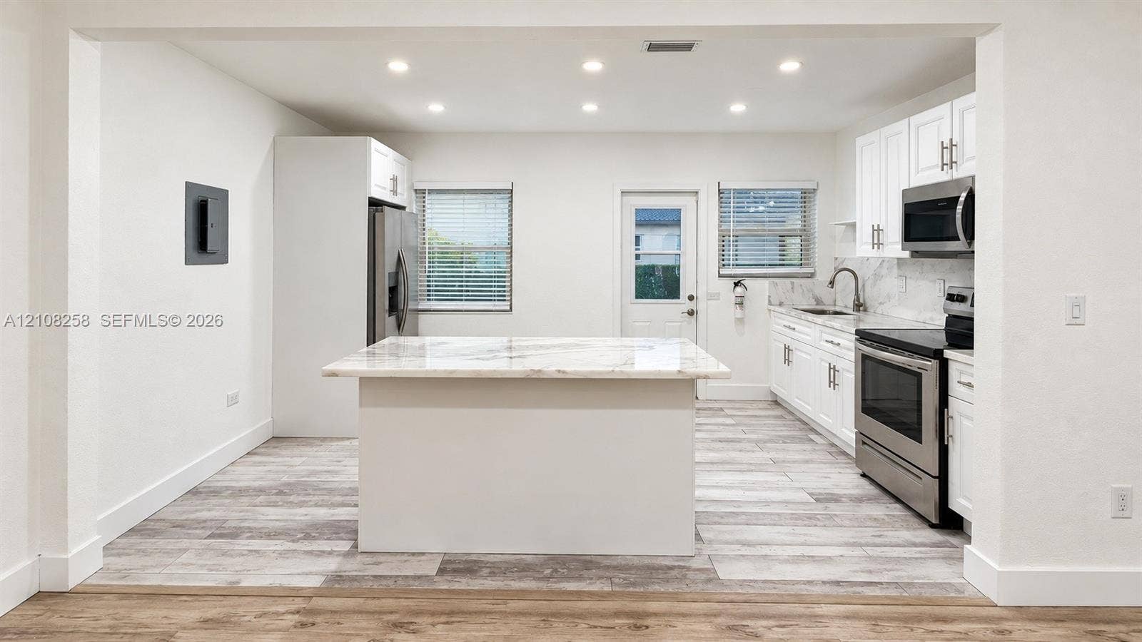 909 NE 111th Street, #909, Biscayne Park, Biscayne Park, FL 33161 Kitchen featuring white shaker-style cabinetry, stone-finish countertops, stainless steel appliances, a center island, and wood-finish flooring