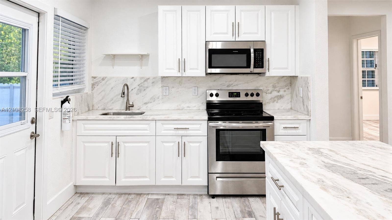 909 NE 111th Street, #909, Biscayne Park, Biscayne Park, FL 33161 Kitchen featuring white shaker-style cabinetry, stone-finish countertops with matching backsplash, stainless steel appliances, and wood-finish flooring