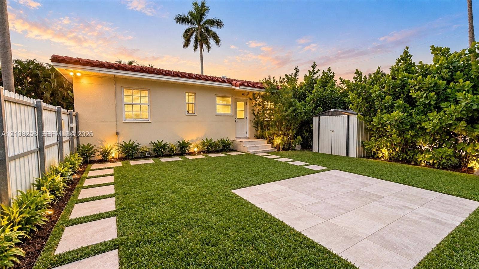 909 NE 111th Street, #909, Biscayne Park, Biscayne Park, FL 33161 Rear exterior featuring a tile roof, paved patio area, grid-patterned stone walkway, and privacy fencing