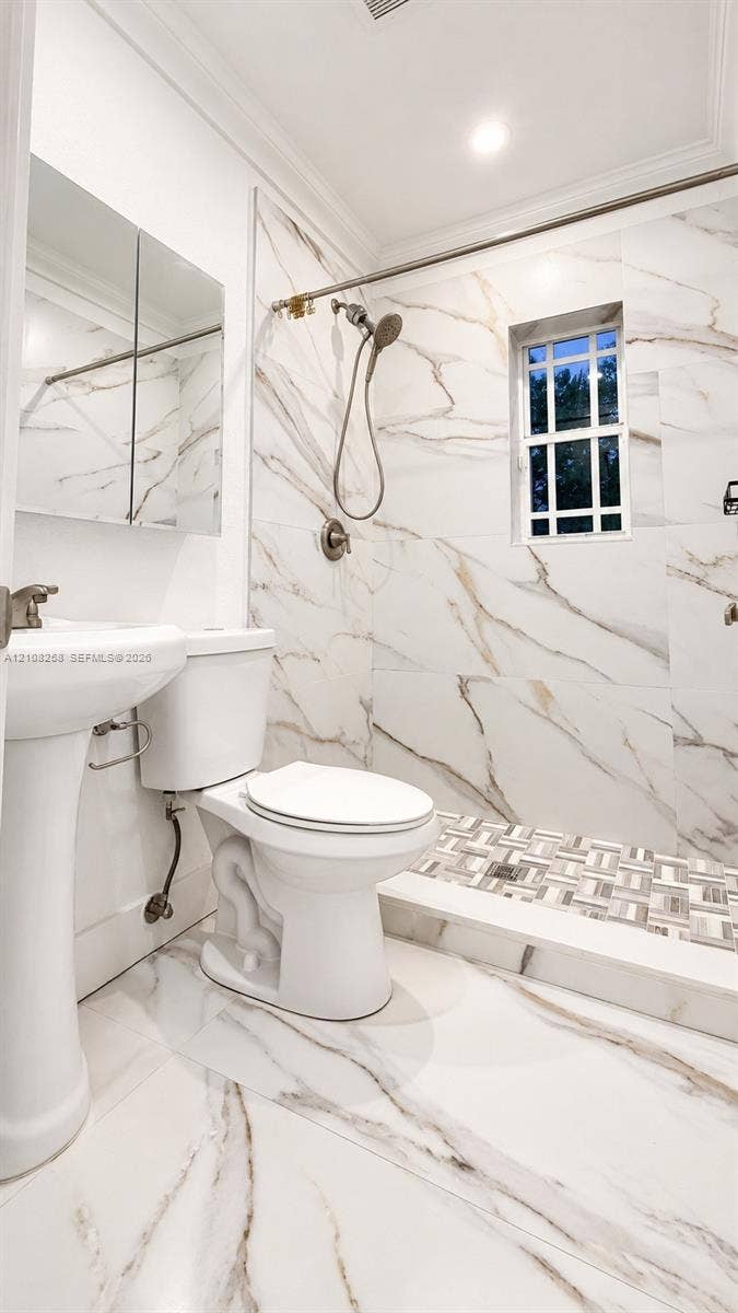 909 NE 111th Street, #909, Biscayne Park, Biscayne Park, FL 33161 Bathroom featuring floor-to-ceiling large-format stone-patterned tile, walk-in shower with decorative mosaic tile flooring, pedestal sink, and built-in medicine cabinet