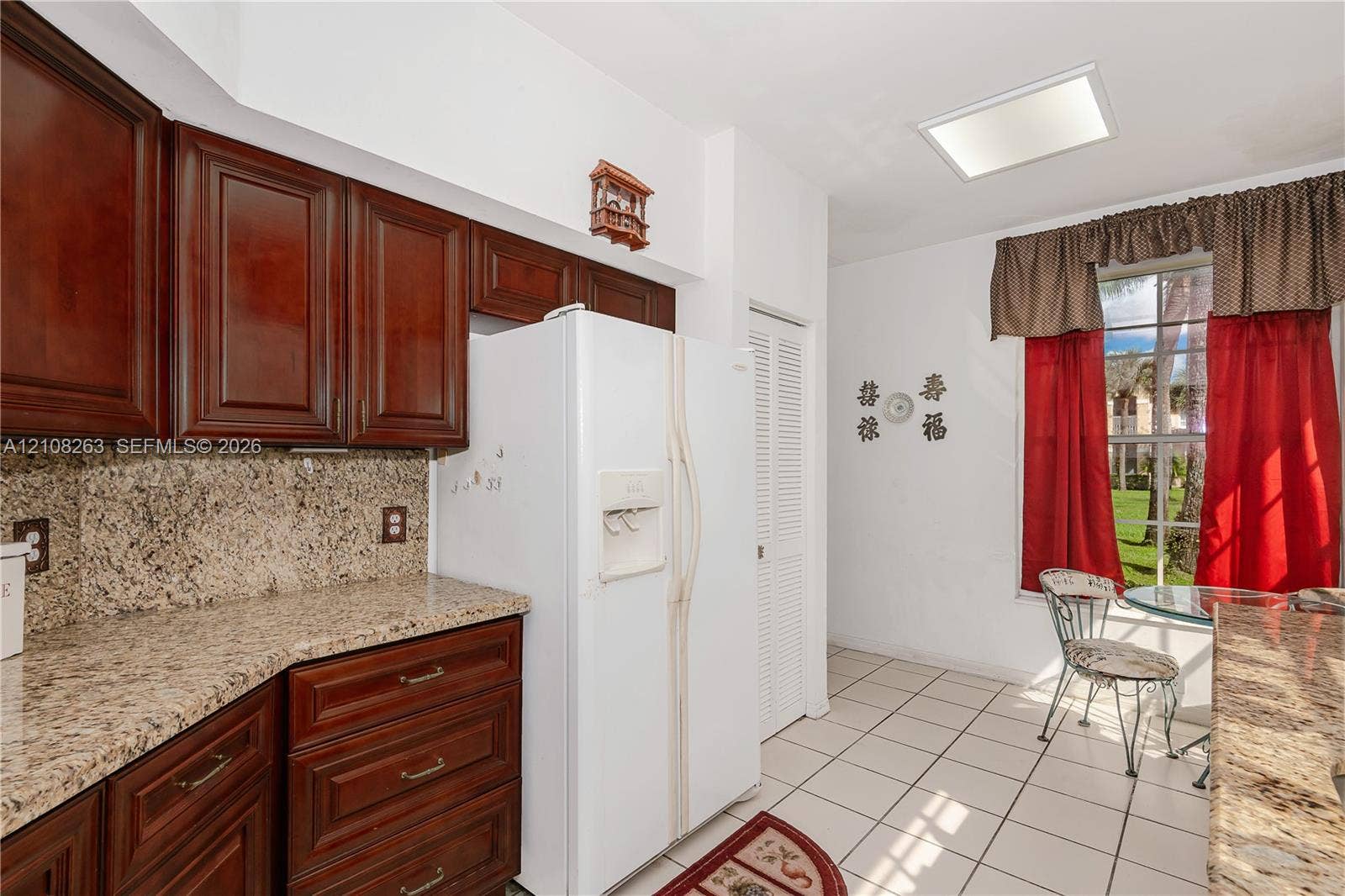 14817 Balgowan Road, #102-5, Miami Lakes, FL 33016 Kitchen featuring dark-stained wood cabinetry, stone countertops, tiled flooring, a skylight, and a large window