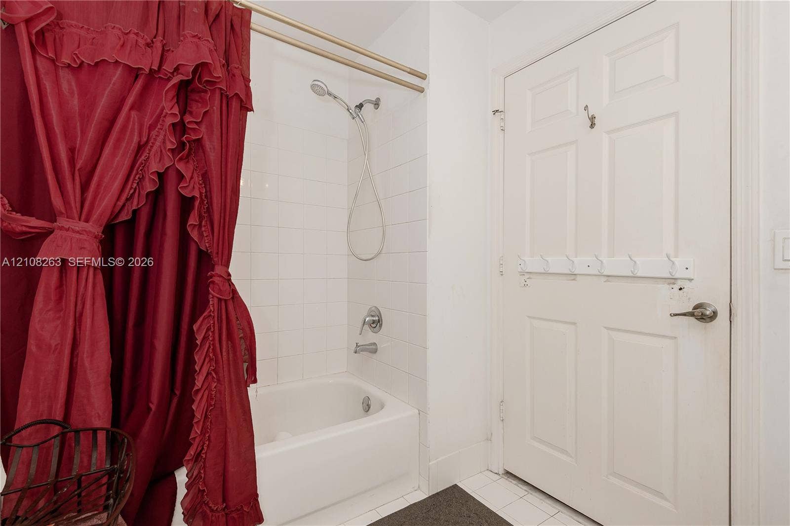 14817 Balgowan Road, #102-5, Miami Lakes, FL 33016 Bathroom featuring a white composite bathtub, wall-mounted shower head, tiled surround, and a six-panel door with integrated hardware