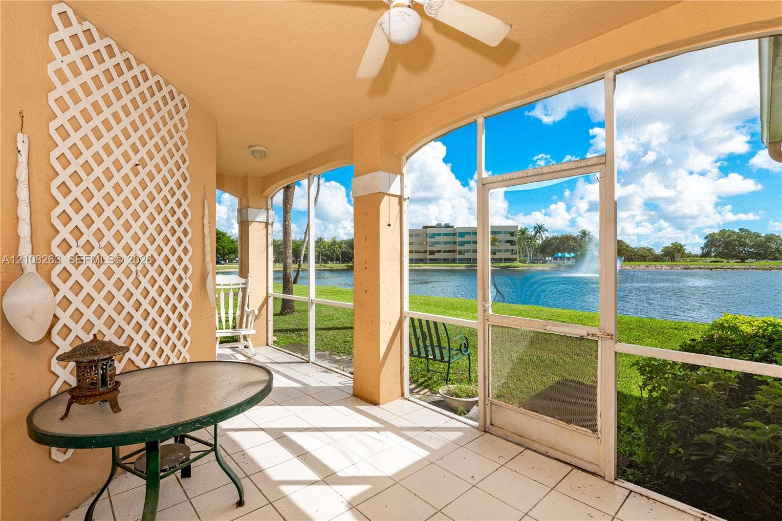 14817 Balgowan Road, #102-5, Miami Lakes, FL 33016 Screened-in lanai featuring white ceramic tile flooring, a mounted ceiling fan, decorative wall-mounted latticework, and water frontage