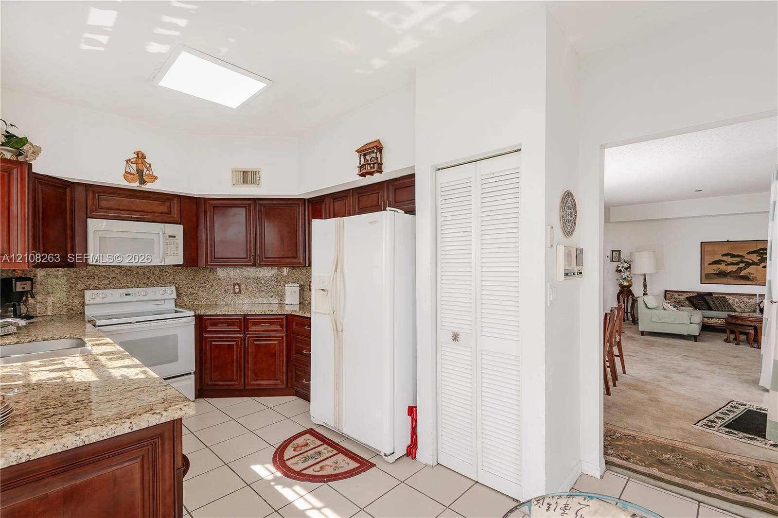 14817 Balgowan Road, #102-5, Miami Lakes, FL 33016 Kitchen featuring dark wood cabinetry, stone-surface countertops, tile flooring, and a recessed skylight