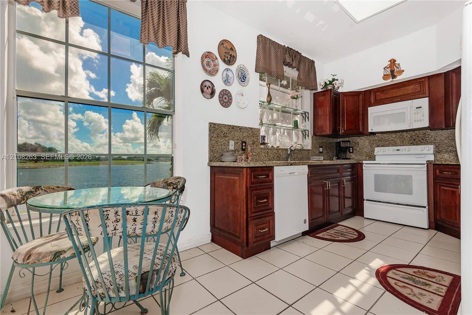 14817 Balgowan Road, #102-5, Miami Lakes, FL 33016 Kitchen featuring raised-panel wood cabinetry, stone countertops, tiled flooring, and floor-to-ceiling windows with water scenery