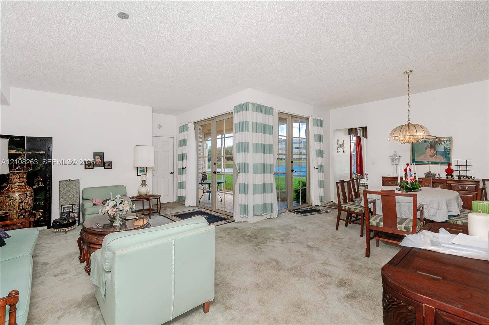 14817 Balgowan Road, #102-5, Miami Lakes, FL 33016 Living area featuring carpeted flooring, two sets of glass-paned doors, and a hanging pendant light fixture