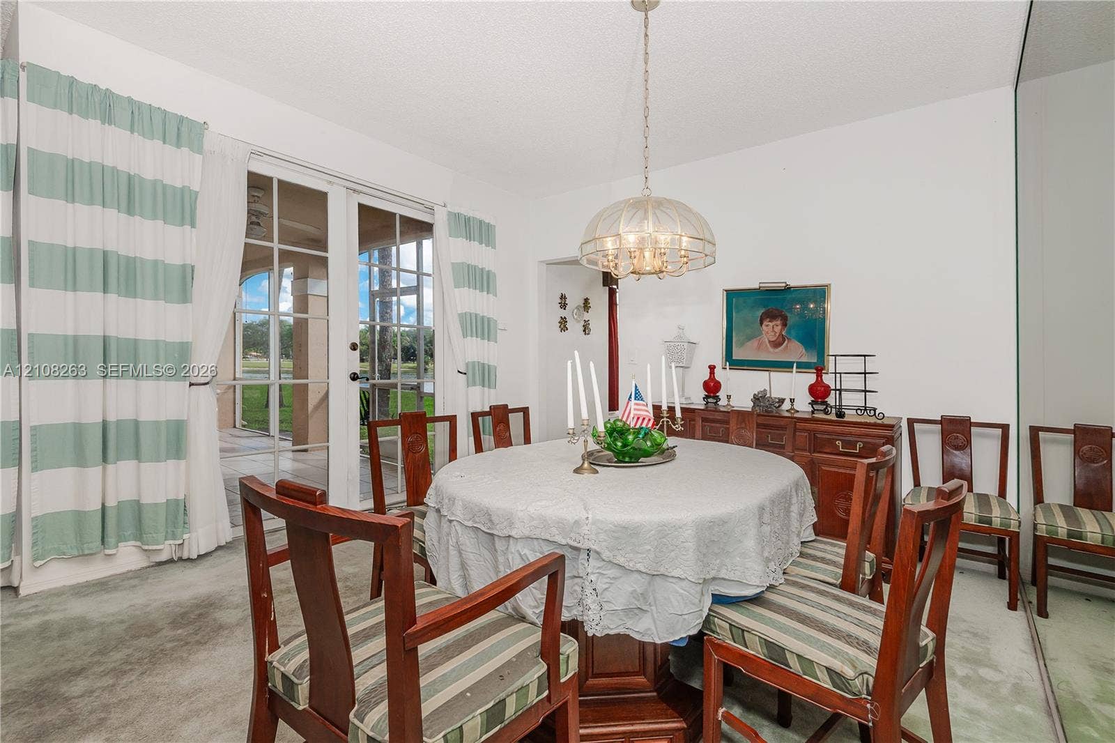 14817 Balgowan Road, #102-5, Miami Lakes, FL 33016 Dining area featuring glass-paned French doors, a metallic dome chandelier, and a full-length wall mirror