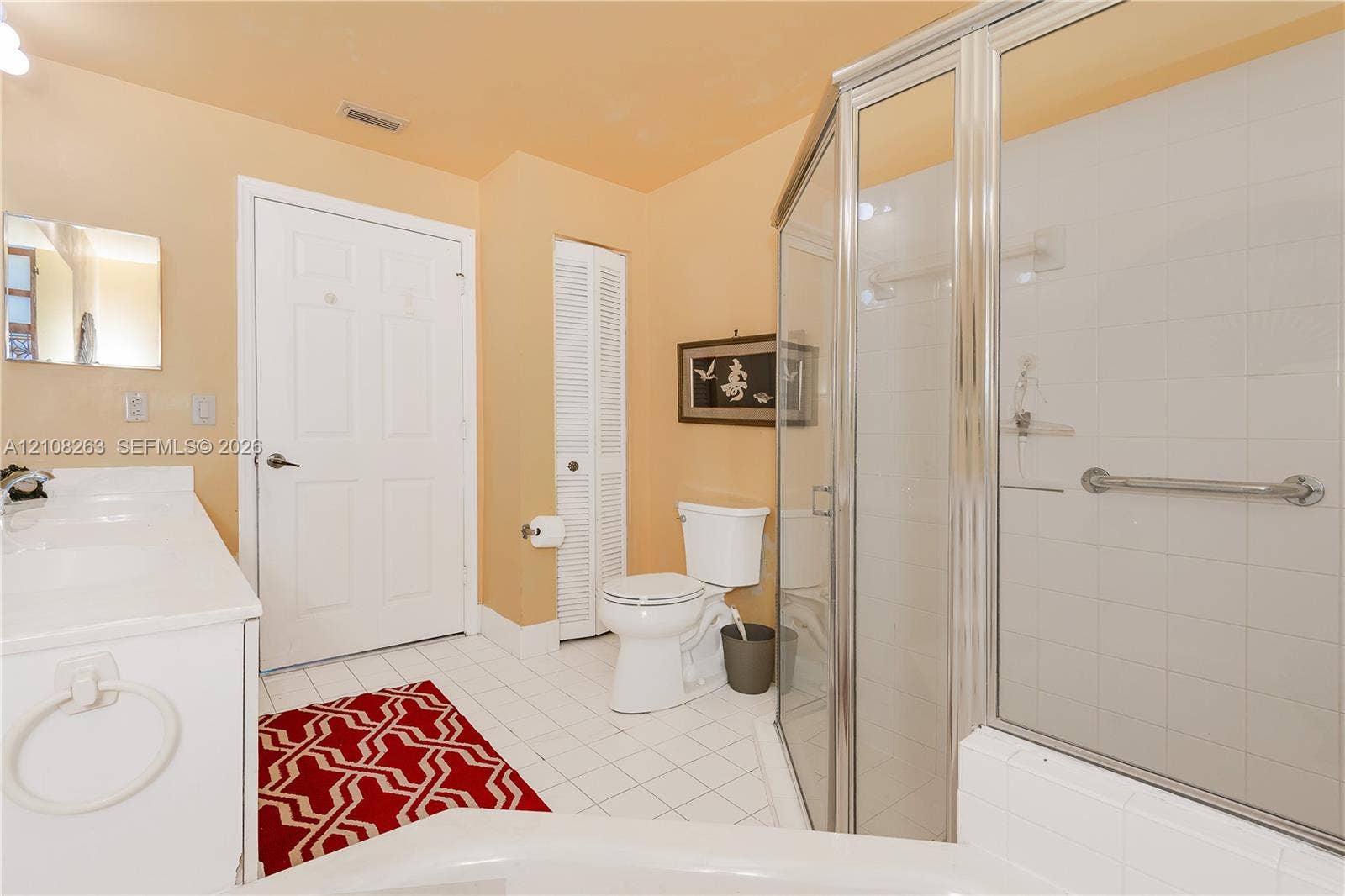 14817 Balgowan Road, #102-5, Miami Lakes, FL 33016 Bathroom featuring a white vanity with a composite countertop, a corner glass-enclosed shower, ceramic tile flooring, and a louvered closet door