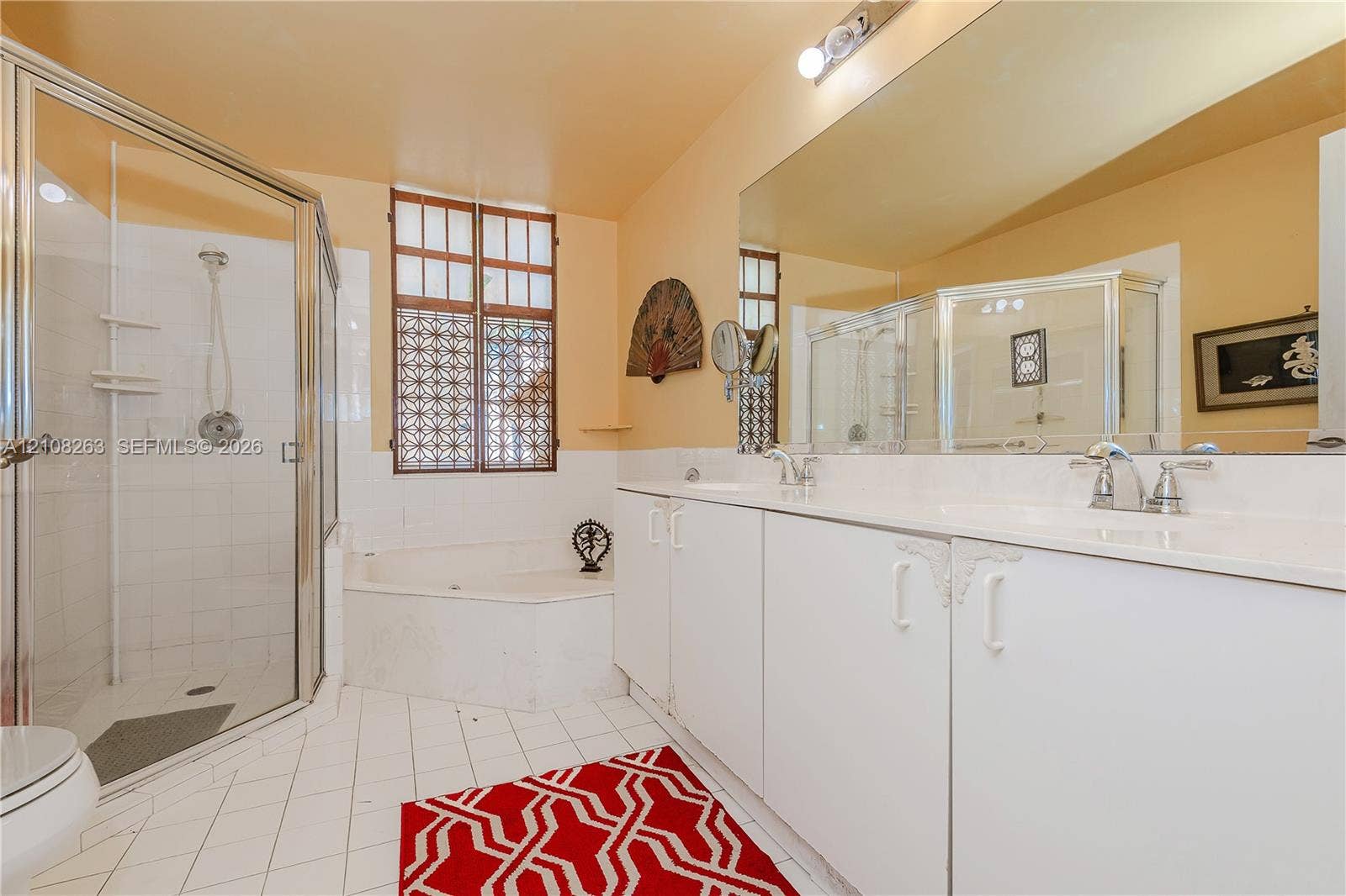 14817 Balgowan Road, #102-5, Miami Lakes, FL 33016 Bathroom featuring a double-sink vanity with white cabinetry, a glass-enclosed shower, a corner jetted soaking tub, large wall-mounted mirror, and tile flooring