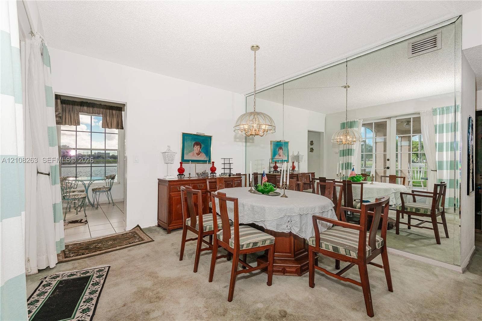 14817 Balgowan Road, #102-5, Miami Lakes, FL 33016 Dining space featuring a floor-to-ceiling wall mirror, a central pendant light fixture, and an entry to an exterior-facing patio
