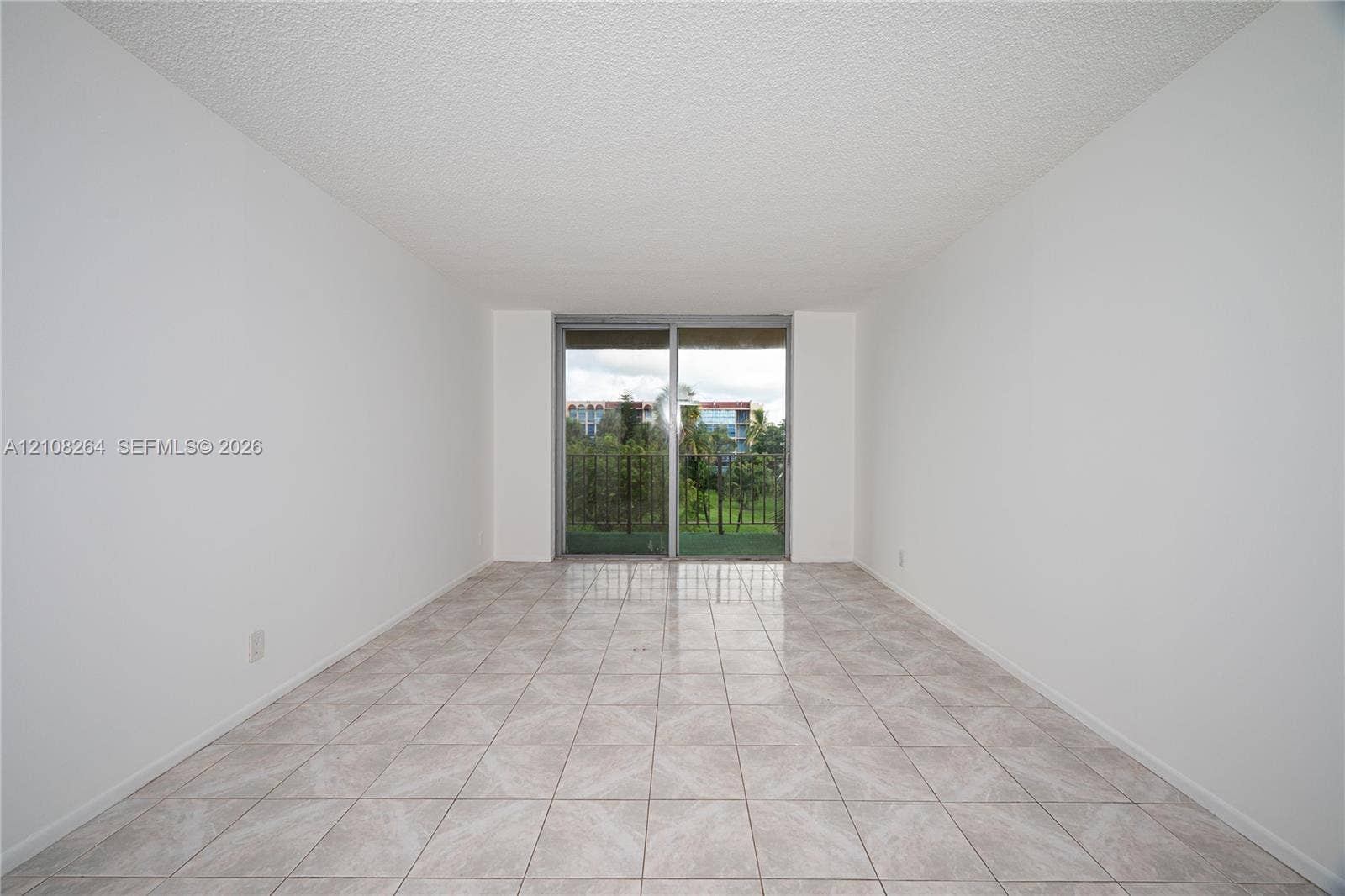 Neutral-toned floor tiles and sliding glass doors leading to a private balcony