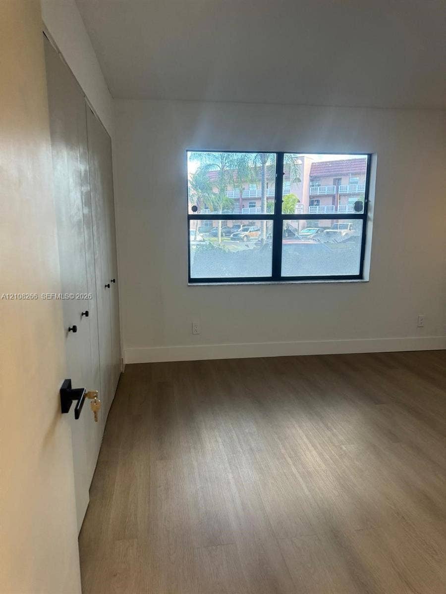 9721 Sunrise Lakes Boulevard, #108, Sunrise, FL 33322 Interior space featuring wood-finish flooring, a multi-panel window with a dark frame, and built-in closet storage with matte black hardware