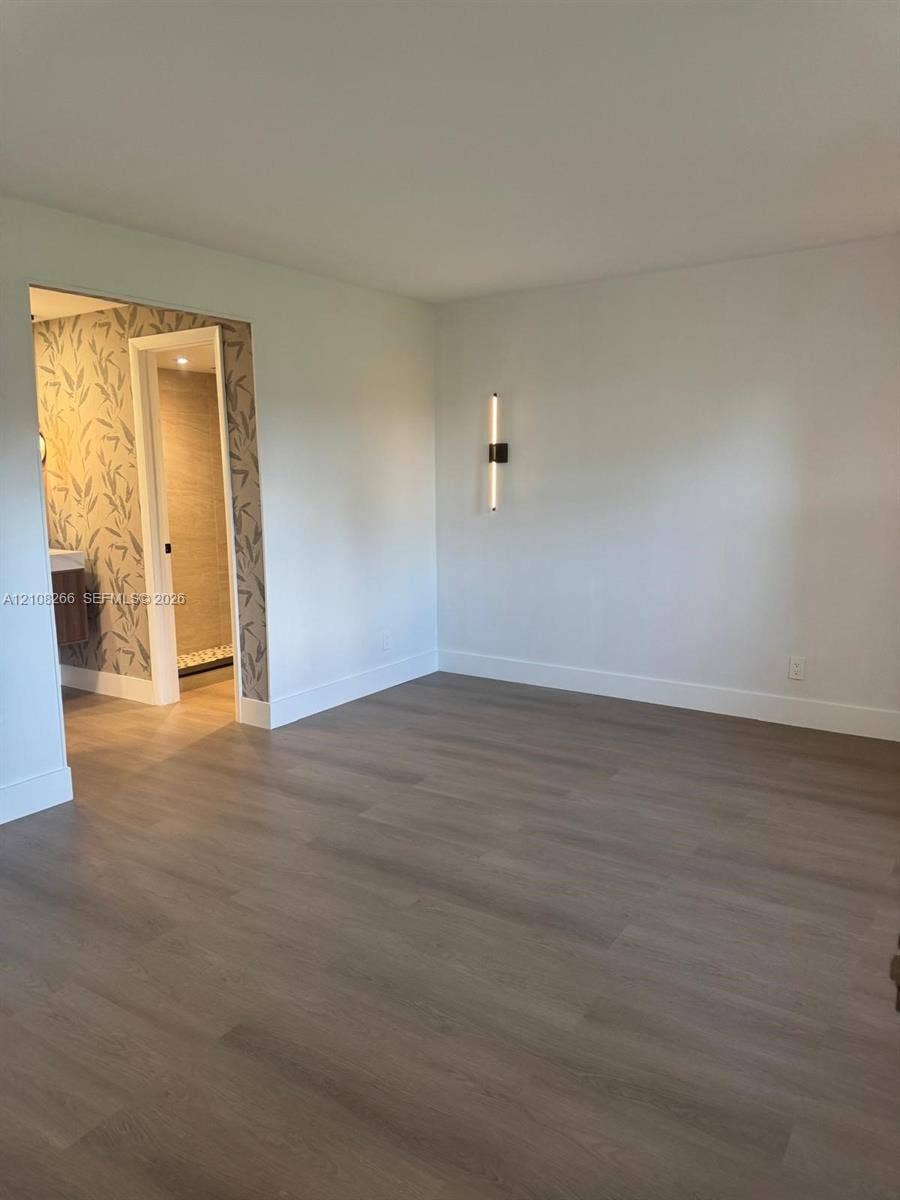 9721 Sunrise Lakes Boulevard, #108, Sunrise, FL 33322 Wood-finish flooring, minimalist wall-mounted linear lighting, and patterned wall covering surrounding an interior doorway