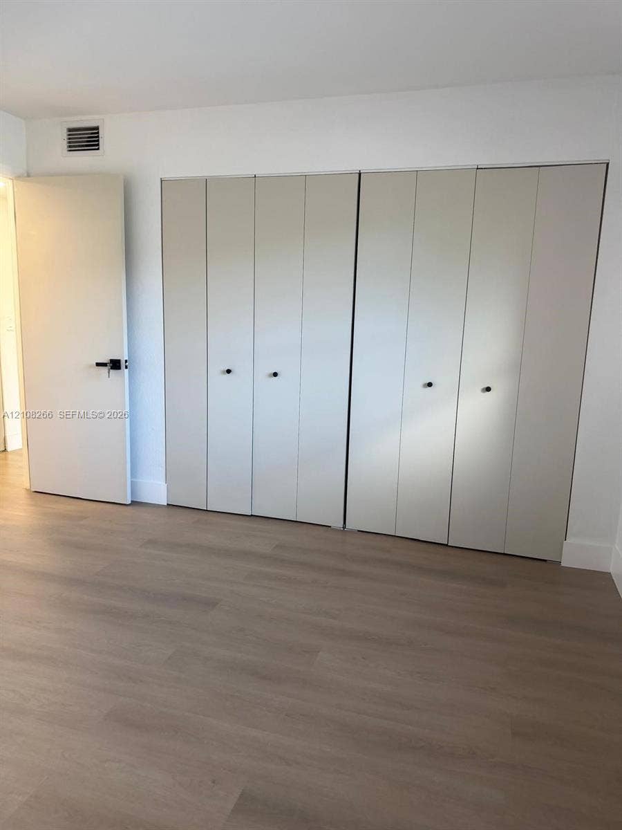9721 Sunrise Lakes Boulevard, #108, Sunrise, FL 33322 Wood-finish flooring, full-wall built-in cabinetry with neutral panel doors, matte black hardware, and crisp white wall finishes