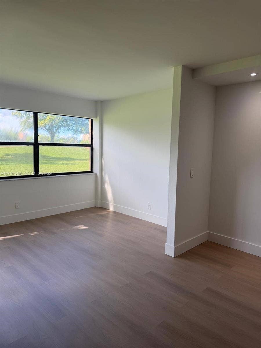 9721 Sunrise Lakes Boulevard, #108, Sunrise, FL 33322 Room featuring wood-finish flooring, neutral walls, and a large horizontal window with black framing