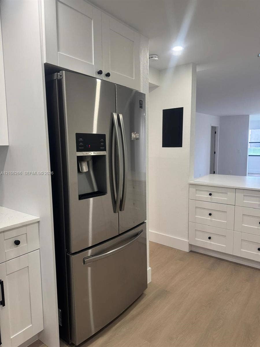 9721 Sunrise Lakes Boulevard, #108, Sunrise, FL 33322 Kitchen featuring white shaker-style cabinetry, wood-finish flooring, stainless steel French door refrigerator, and white countertops