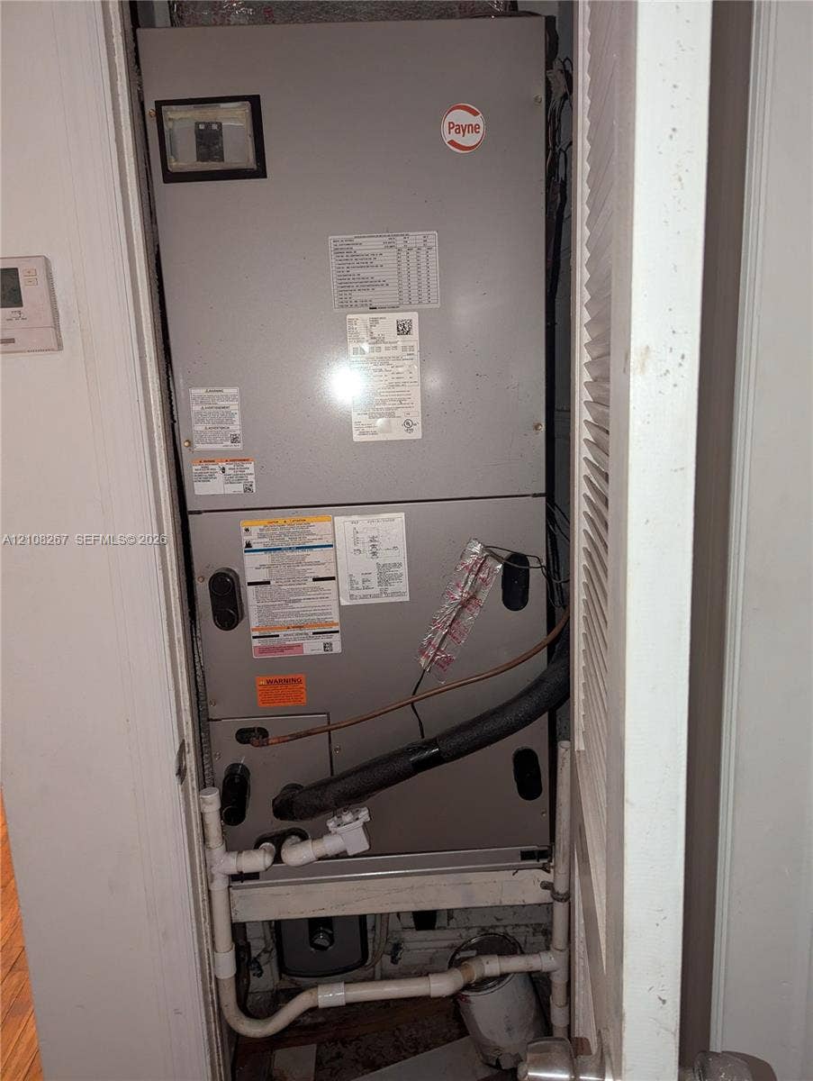 Payne furnace unit featuring a metal enclosure with built-in plumbing connections and a mounted digital thermostat