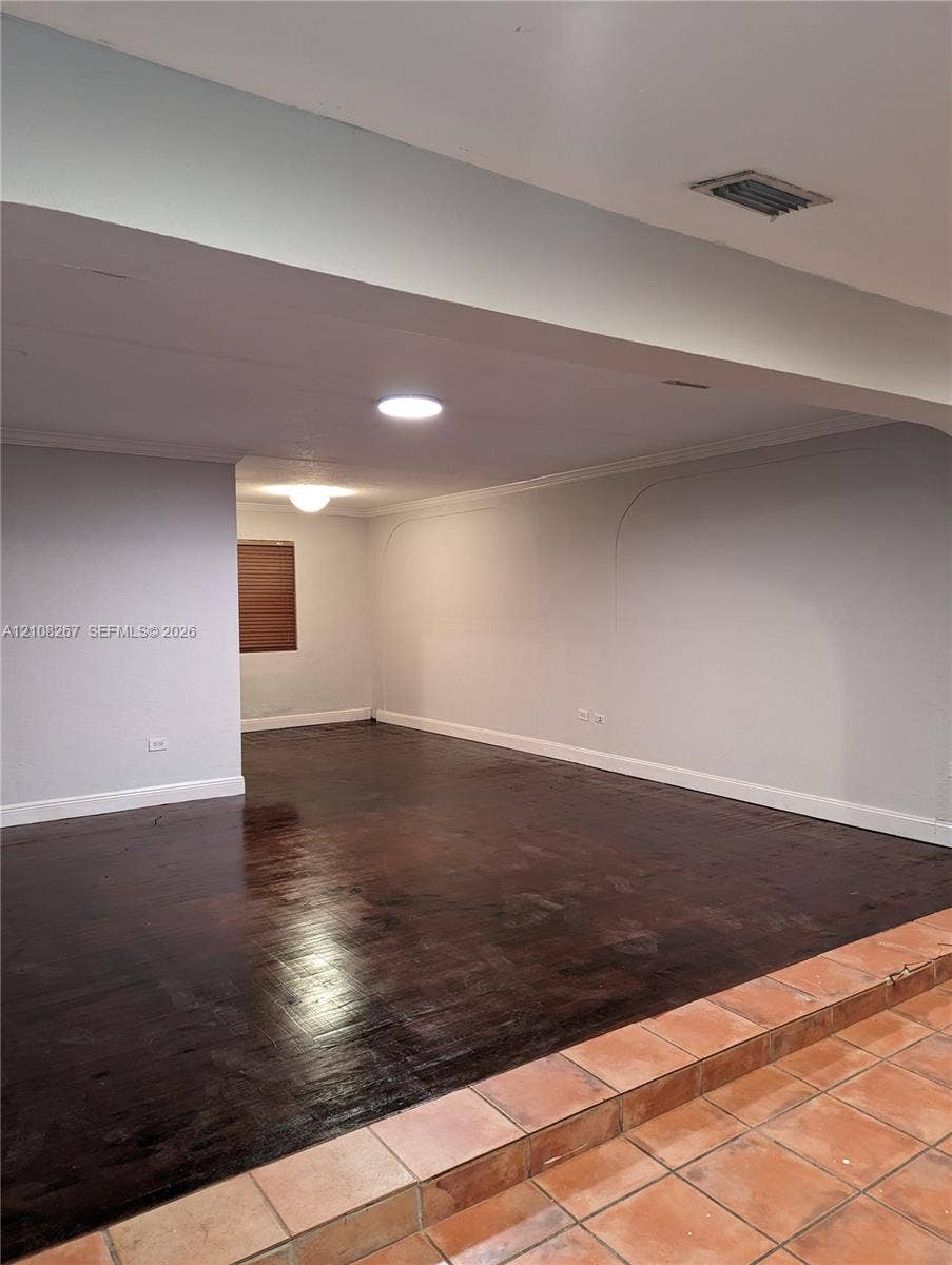 Sunken living area featuring dark wood-finish flooring, terra cotta tile steps, recessed ceiling lighting, and arch-top wall detailing
