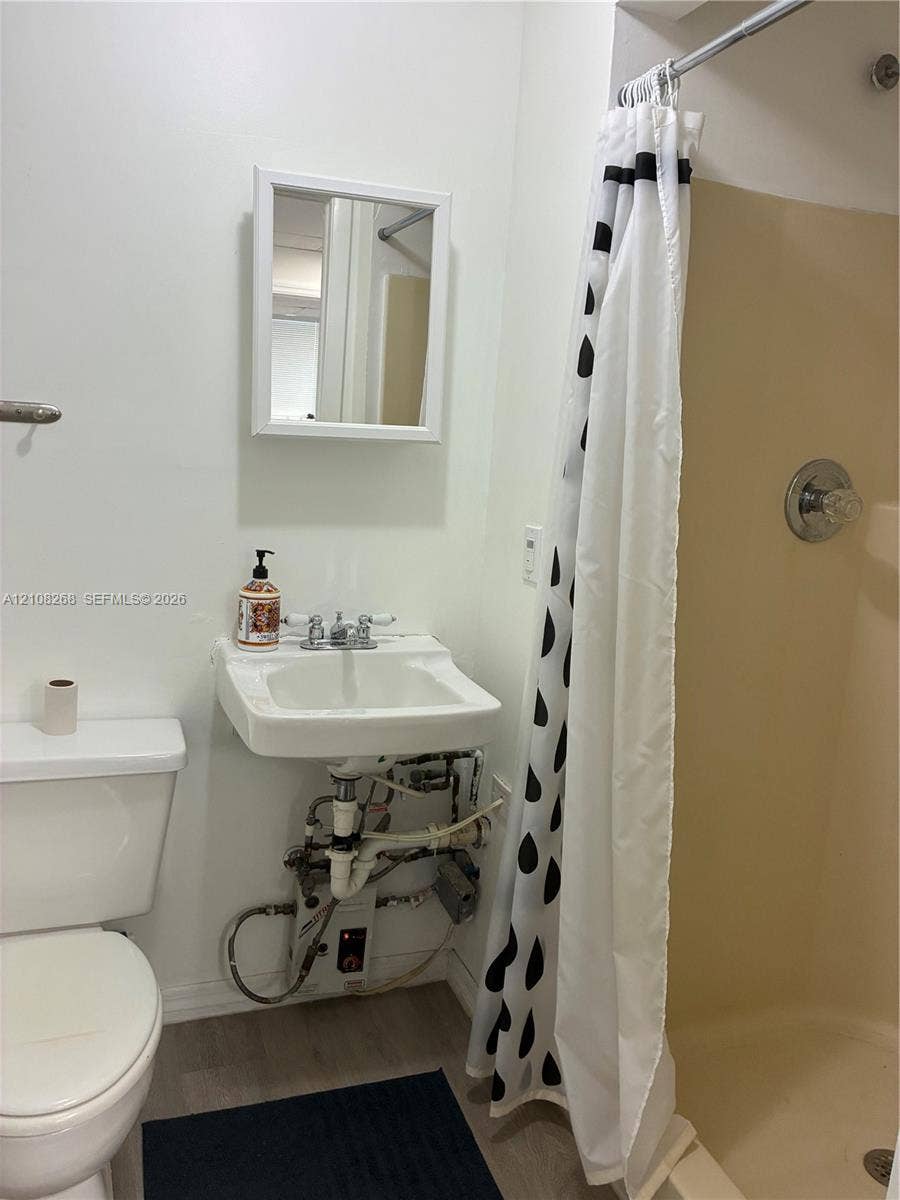Wall-mounted sink with dual-handle chrome faucet, medicine cabinet with white frame, and enclosed shower stall with integrated chrome fixtures