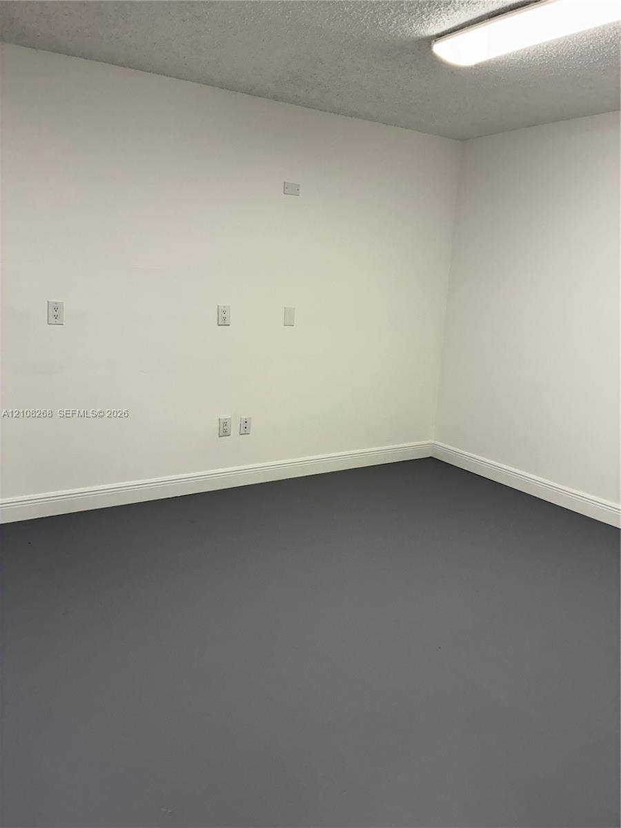 Interior room featuring gray painted flooring, white walls, and a ceiling-mounted light fixture