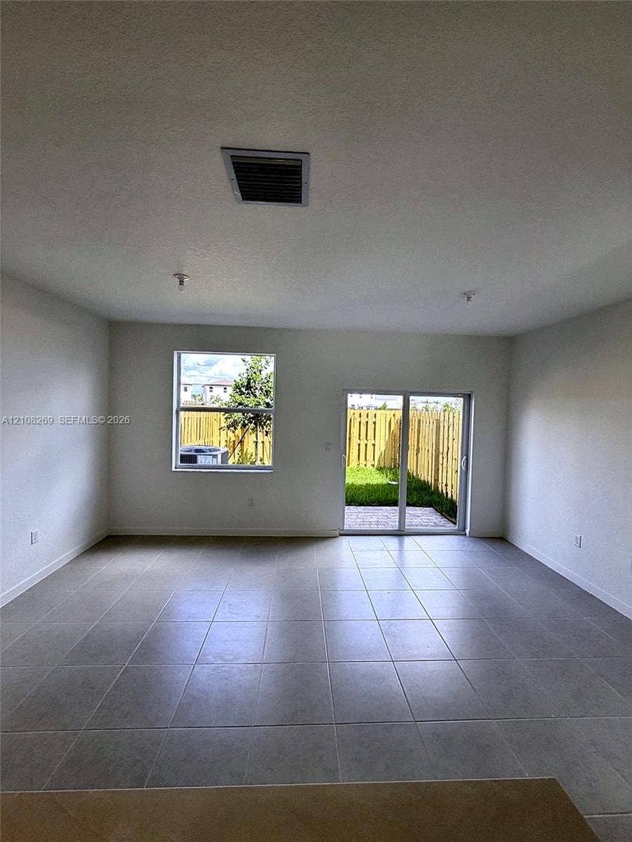 2593 SE 25th Drive, Homestead, Homestead, FL 33035 Open-concept interior featuring large-format ceramic tile flooring, neutral walls, a single-hung window, and a sliding glass door providing external access