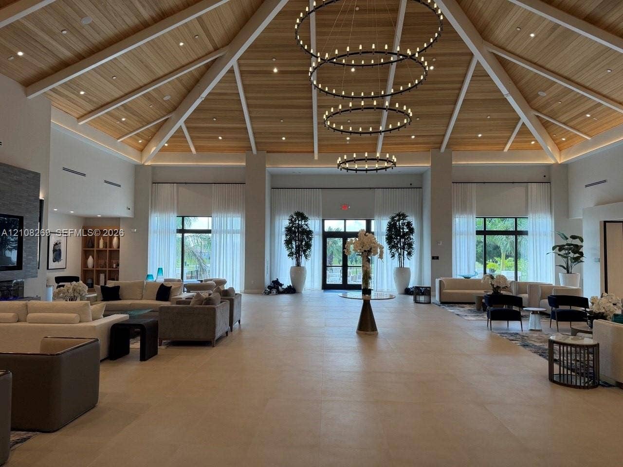 2593 SE 25th Drive, Homestead, Homestead, FL 33035 Vaulted wood-plank ceiling featuring exposed beams, stacked three-tier ring chandeliers, large-format tile flooring, and floor-to-ceiling windows