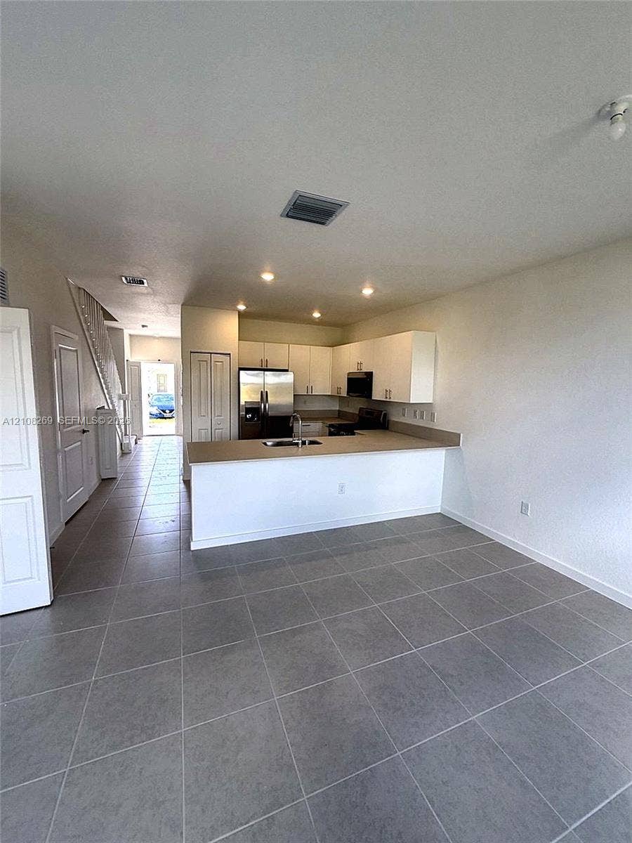 2593 SE 25th Drive, Homestead, Homestead, FL 33035 Kitchen featuring white cabinetry, solid-surface countertops, stainless steel appliances, and large-format tile flooring