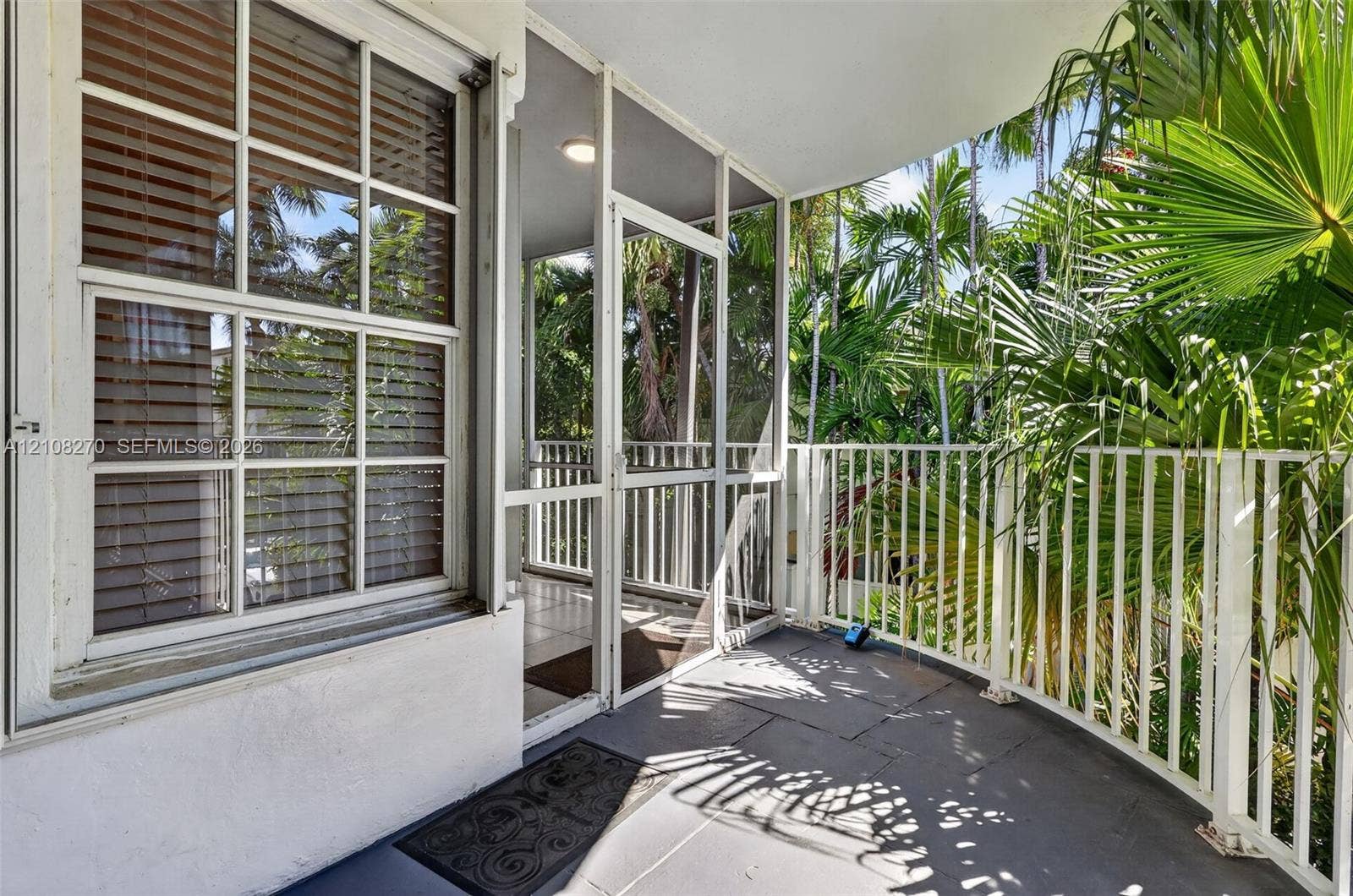 1125 99th Street, #12, Bay Harbor Islands, FL 33154 Covered balcony featuring tile flooring, white metal railing, and a screen enclosure