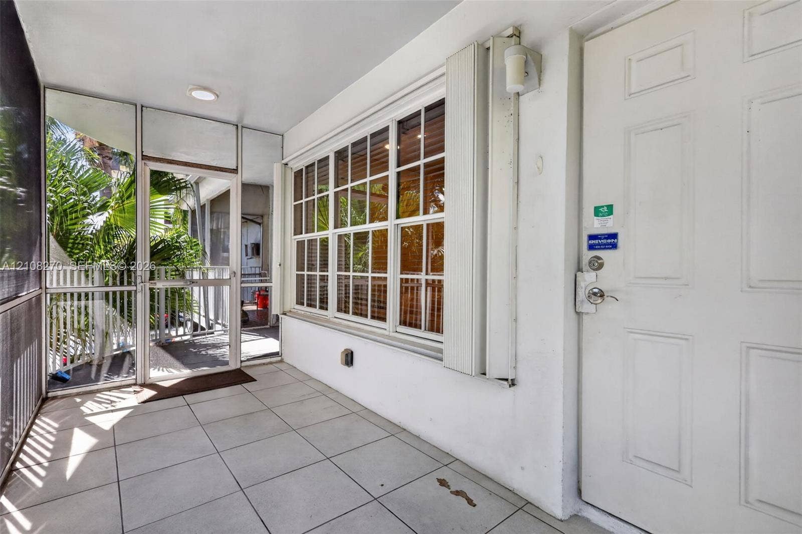 1125 99th Street, #12, Bay Harbor Islands, FL 33154 Screened-in porch featuring tiled flooring, a multi-pane window with aluminum framing, and an exterior door